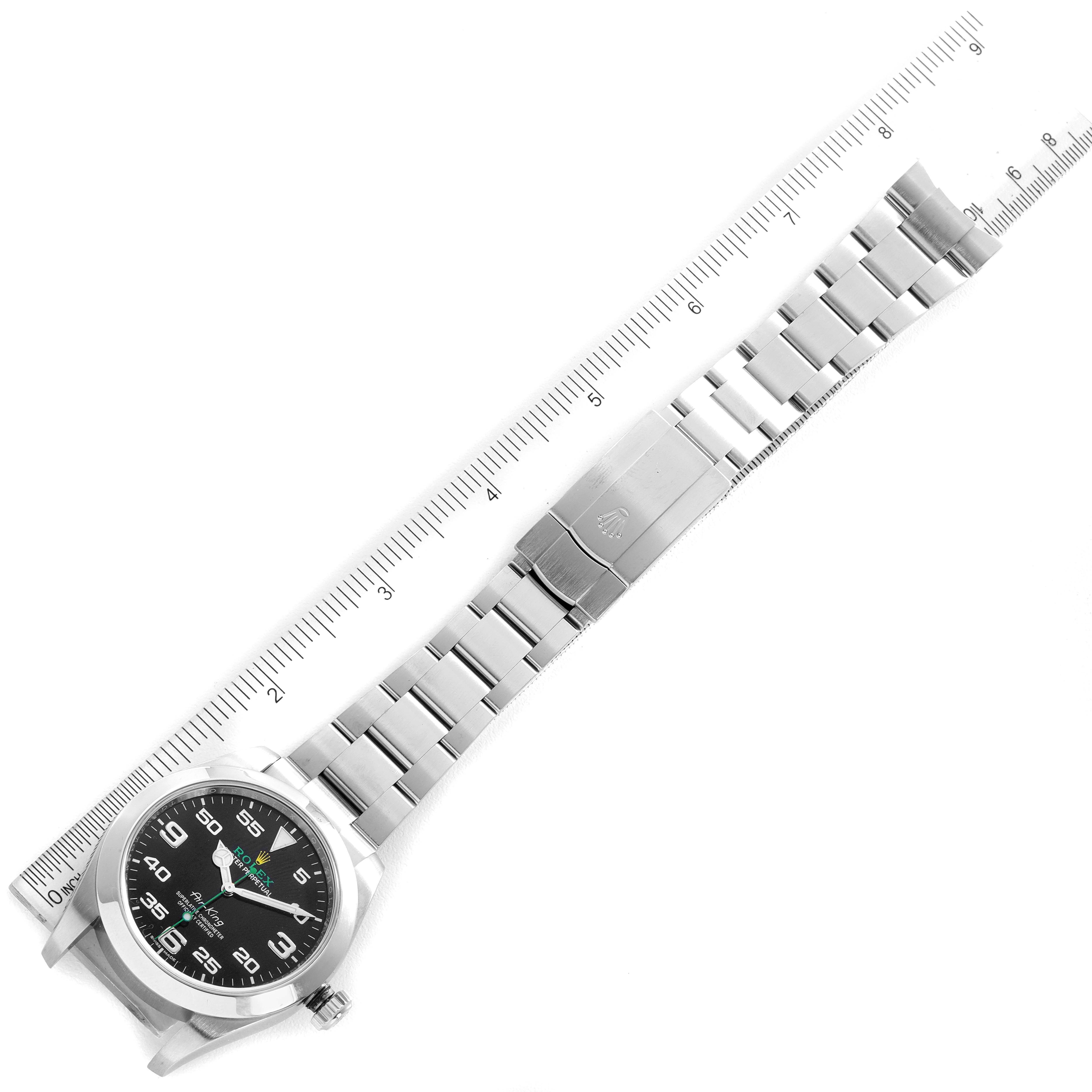 The image shows a top-down view of a Rolex Air-King 116900 Men's Stainless Steel Black Dial 116900 Men's Stainless Steel Black Dial watch with a stainless steel bracelet alongside a ruler.