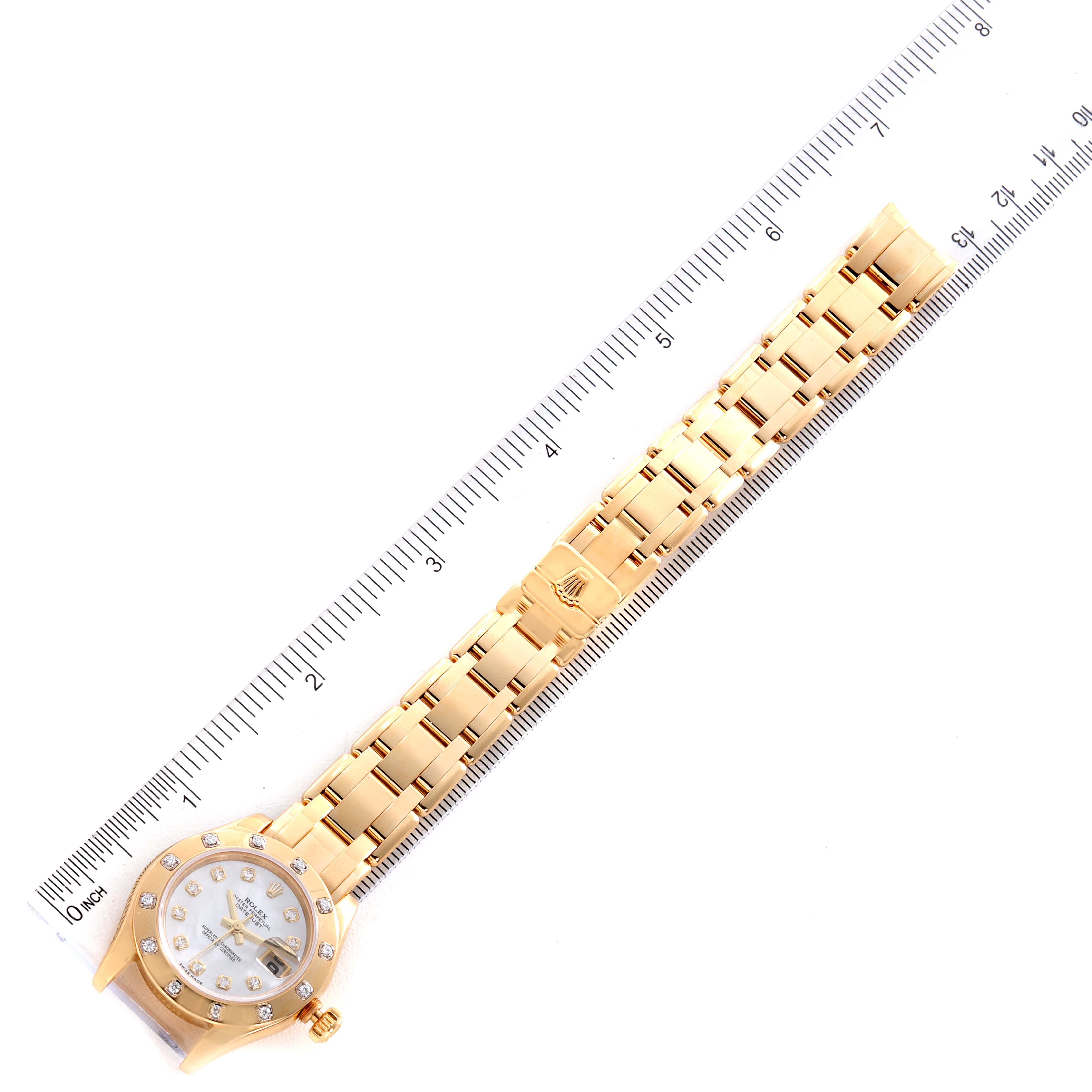 This image shows the Rolex Pearlmaster 80318 Women's Yellow Gold Mother of Pearl Dial 80318 Women's Yellow Gold Mother of Pearl Dial watch laid flat with a ruler beside it, highlighting the watch face and entire band.