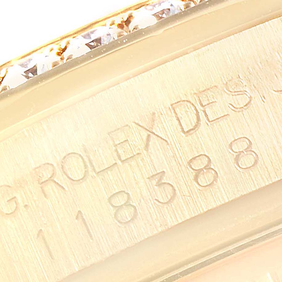 The image shows a close-up of the engraved serial number and part of the diamond-encrusted bezel on a Rolex President 118388 Men
s Yellow Gold Champagne Dial 118388 Men
s Yellow Gold Champagne Dial model watch.