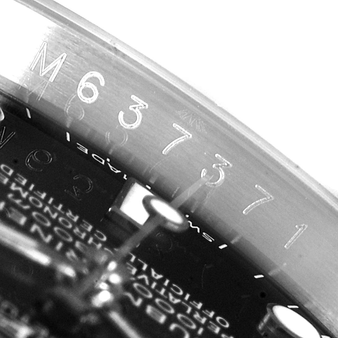 The image shows a close-up view of the serial number engraving on the rehaut of a Rolex Submariner 16610 Men
s Stainless Steel Black Dial 16610 Men
s Stainless Steel Black Dial watch.