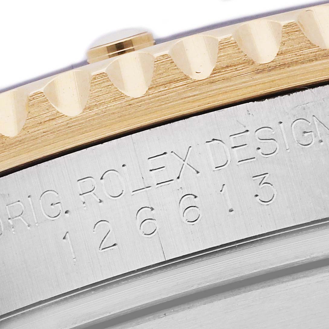 The image shows a close-up of the engraved case and the gold bezel of a Rolex Submariner 126613 Men's Steel and Gold (two tone) Blue Dial 126613 Men's Steel and Gold (two tone) Blue Dial watch.