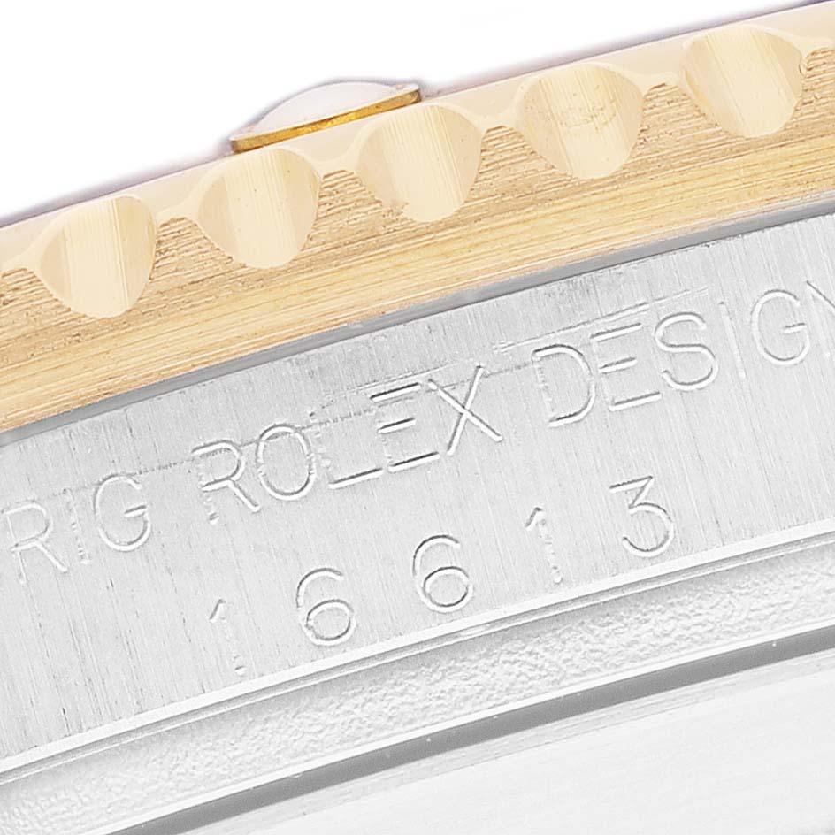 The image shows a close-up of the side of a Rolex Submariner 16613 Men's Steel and Gold (two tone) Champagne Dial, highlighting the bezel edge and engraved serial number.
