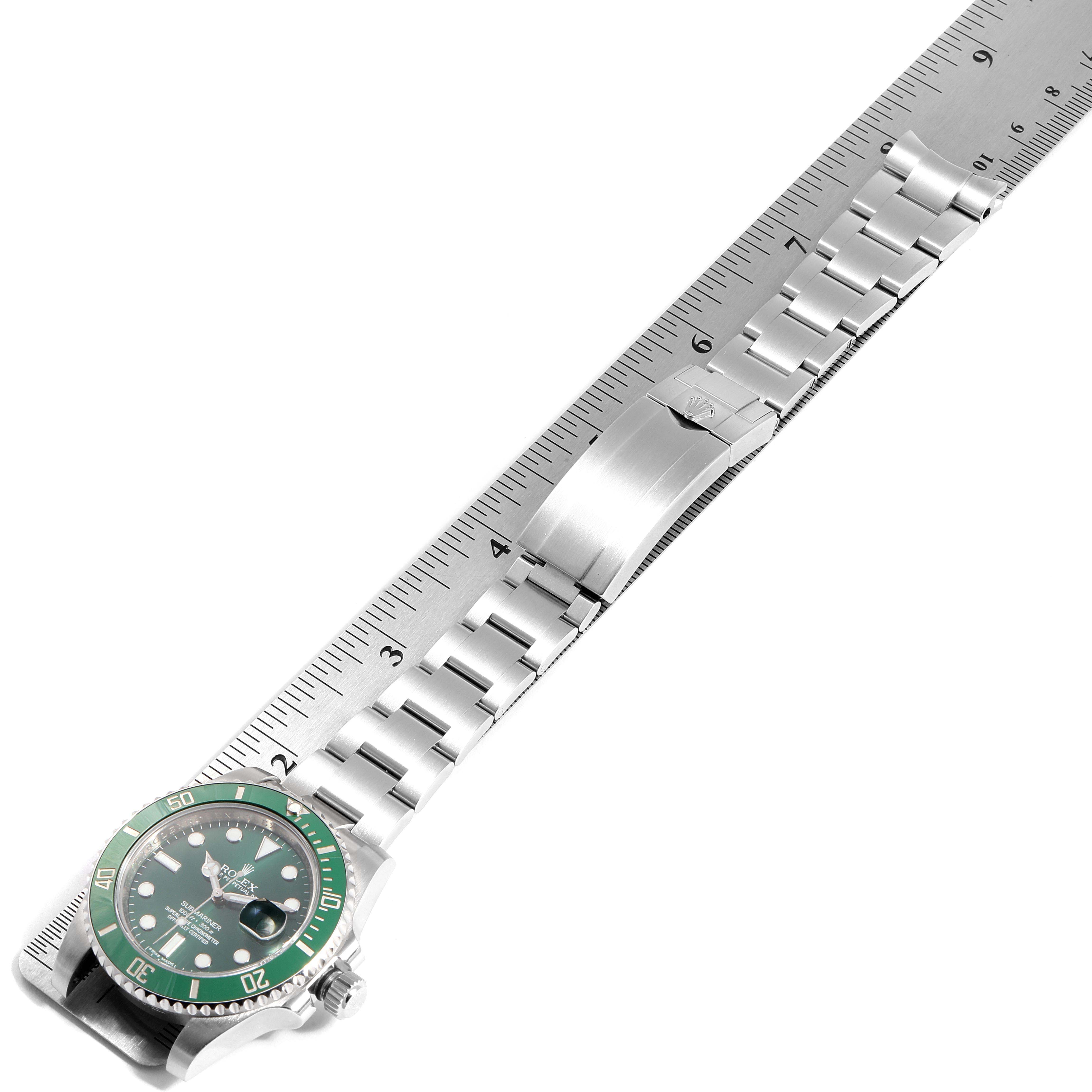 The image shows a top view of a Rolex Submariner 116610LV Men's Stainless Steel Green Dial 116610LV Men's Stainless Steel Green Dial watch and its metal bracelet, along with a ruler for scale.