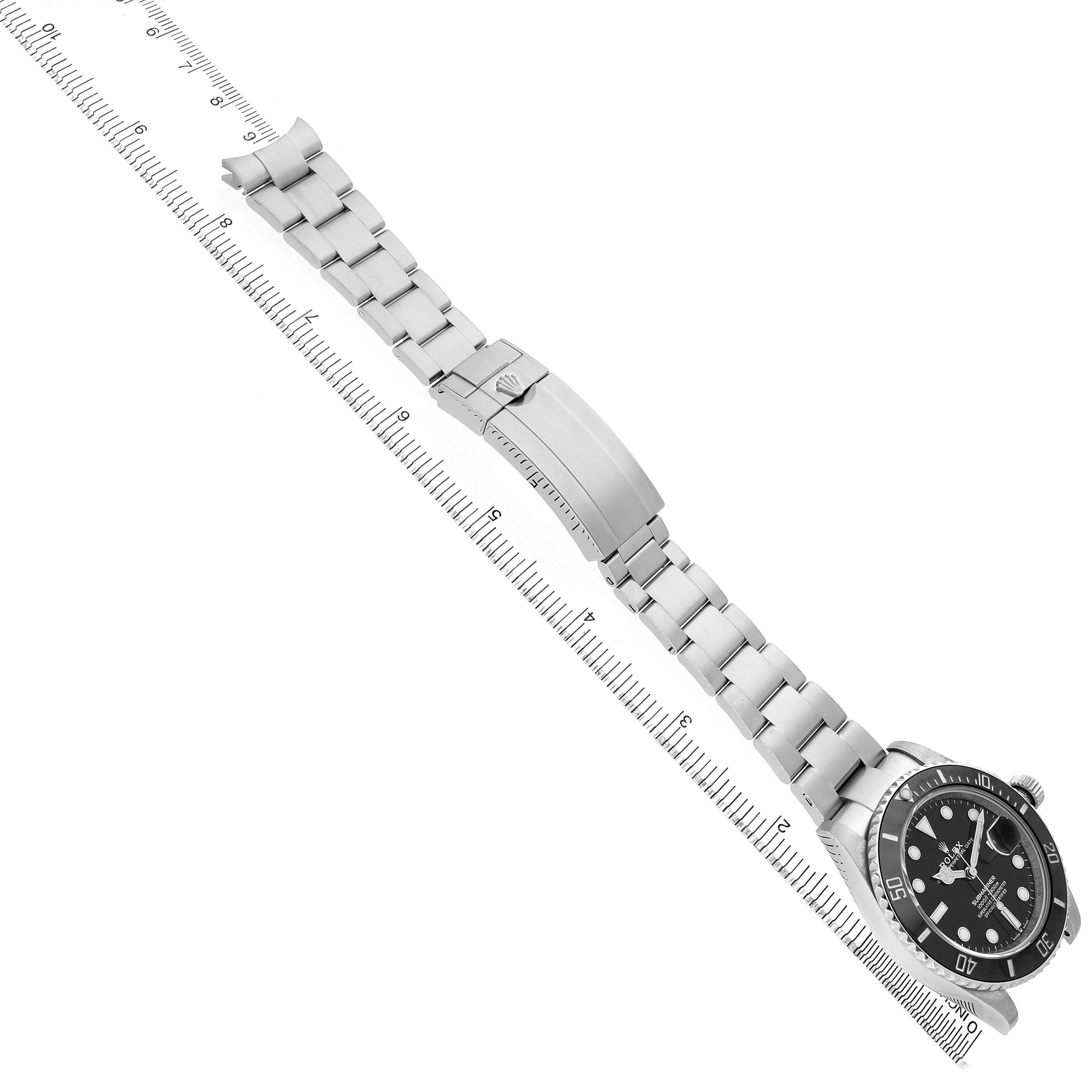 The Rolex Submariner 126610 Men's Stainless Steel Black Dial watch is shown in a top view, displaying the watch face, bracelet, and clasp next to a ruler.