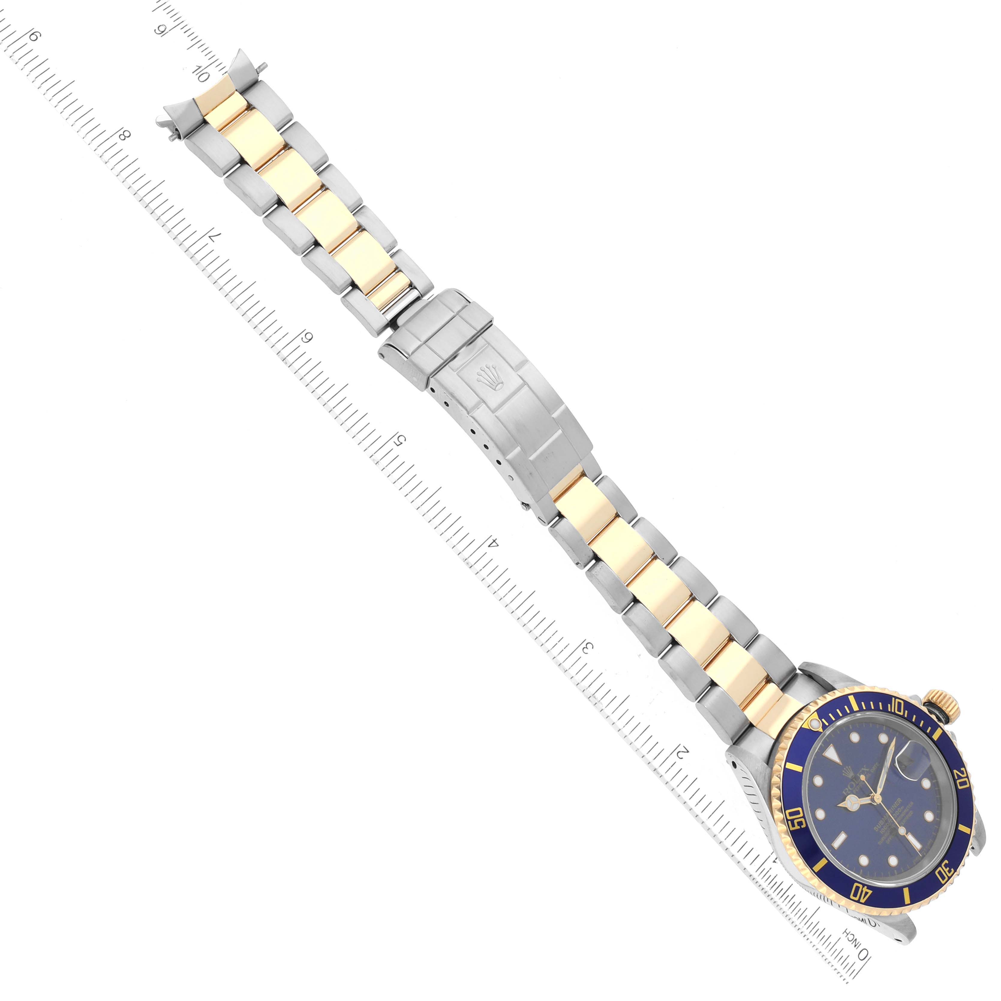 The image shows a Rolex Submariner 16613 Men's Steel and Gold (two tone) Blue Dial 16613 Men's Steel and Gold (two tone) Blue Dial watch photographed from a top-down angle, featuring its bracelet, clasp, and dial.