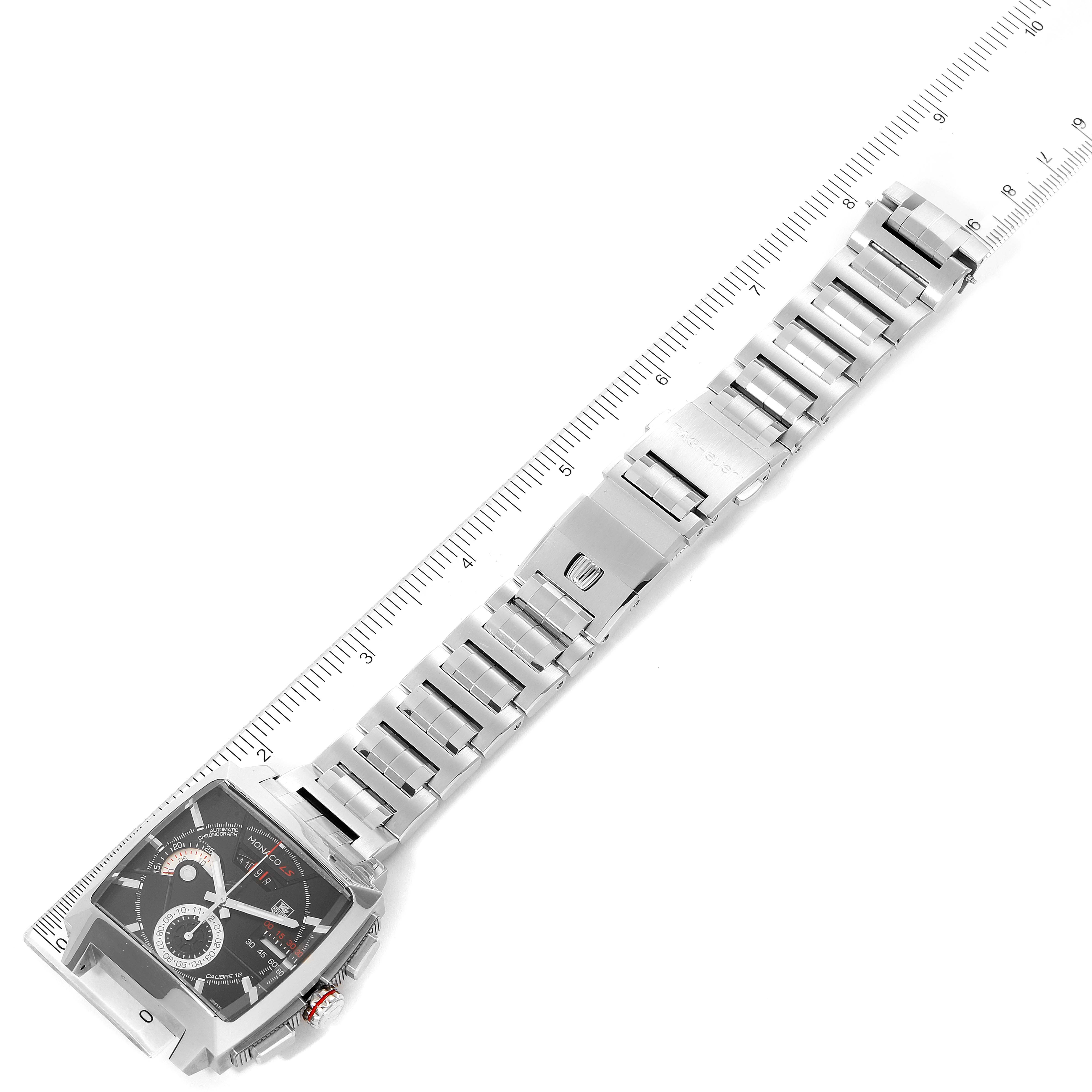 The image shows a top-down view of a Tag Heuer Monaco CAL2110.BA0781 Men's Stainless Steel Black Dial CAL2110.BA0781 Men's Stainless Steel Black Dial watch, highlighting the face and metal bracelet against a ruler.