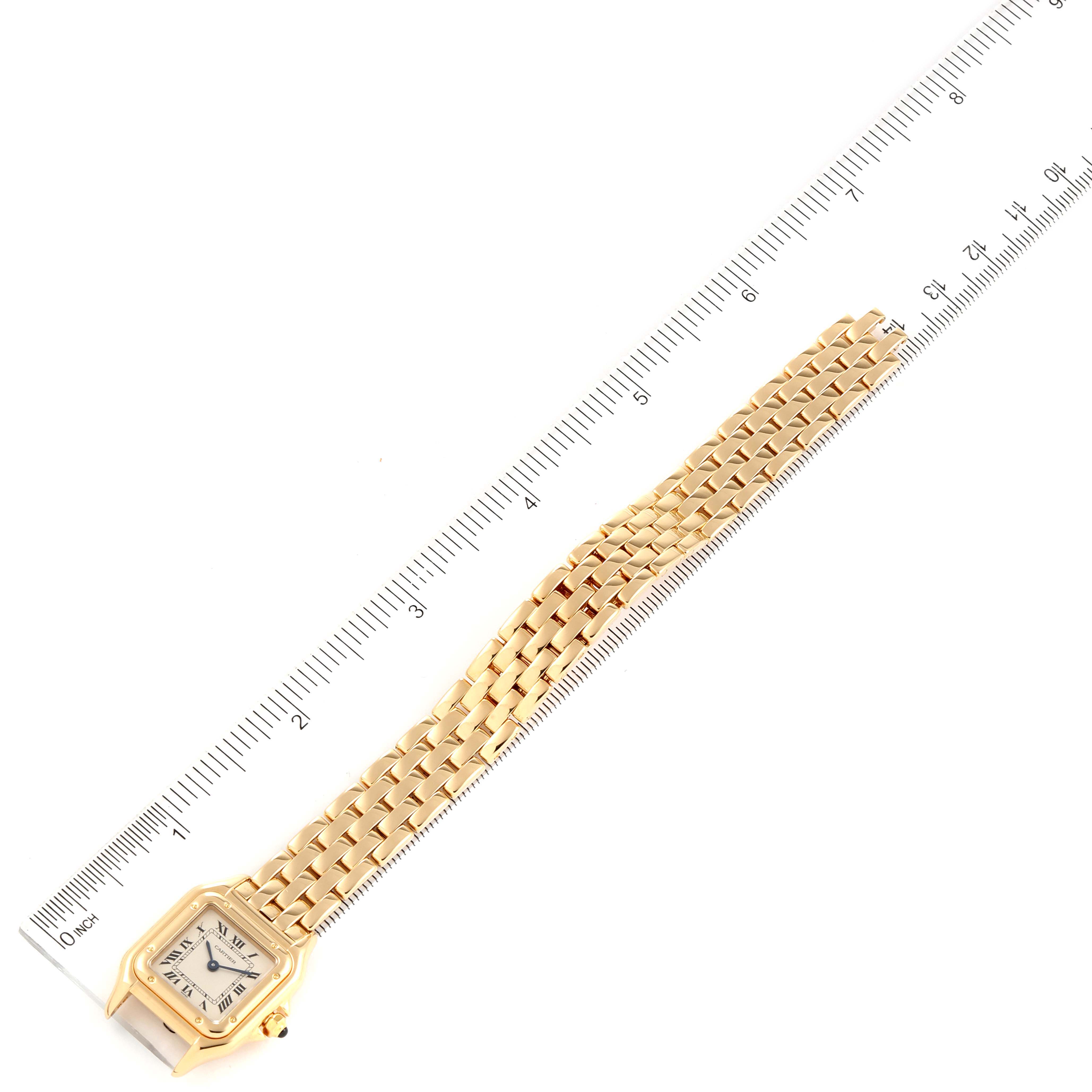 This image shows a top view of a Cartier Panthere W25022B9 Women's Yellow Gold Silver Dial W25022B9 Women's Yellow Gold Silver Dial watch with a gold band, next to a ruler for scale.