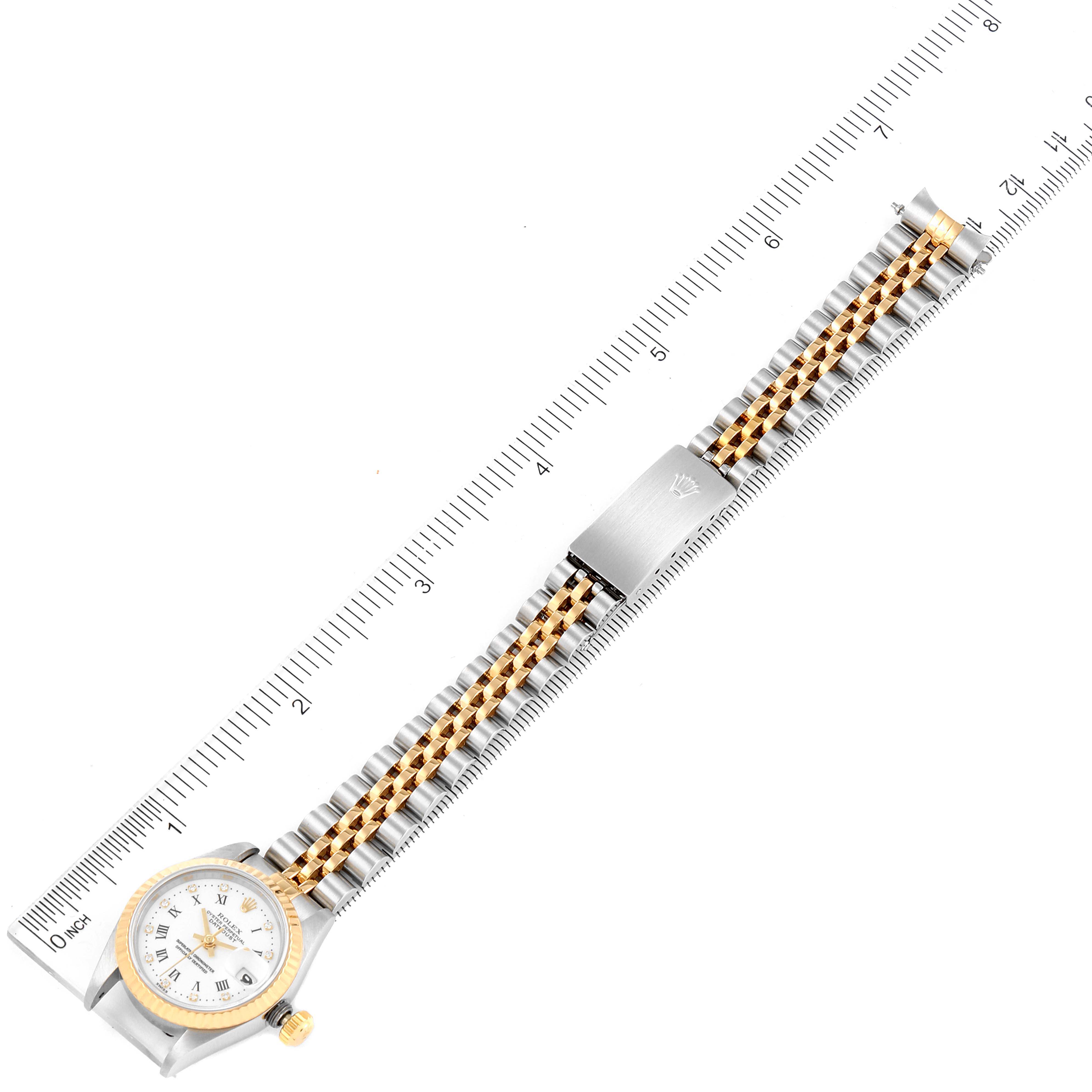 The Rolex Datejust 69173 Women's Steel and Gold (two tone) White Dial 69173 Women's Steel and Gold (two tone) White Dial watch is shown laid flat against a ruler, highlighting the face, bracelet, and clasp.