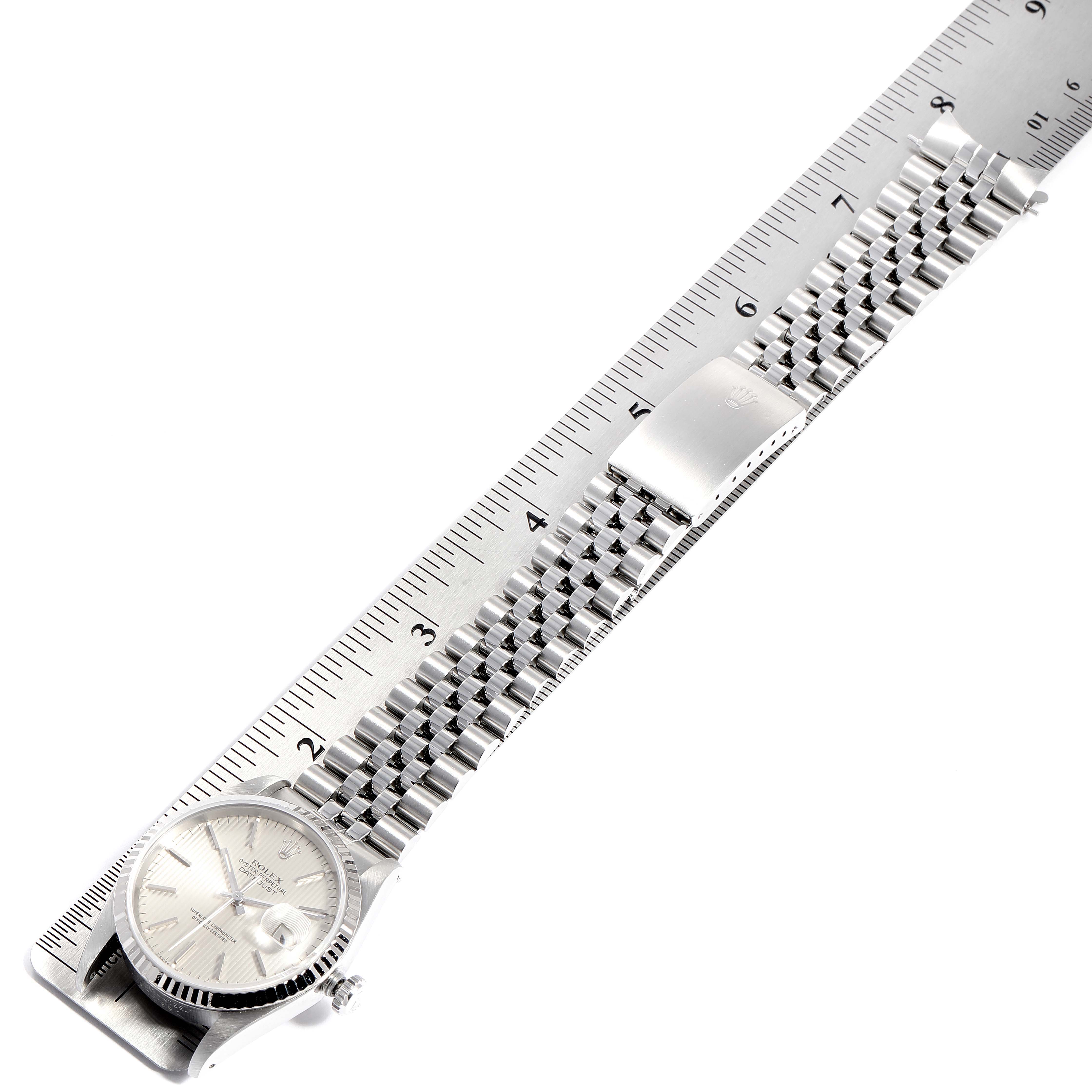 A Datejust model by Rolex, captured side-on, showing the full length of the bracelet alongside a ruler for size reference.