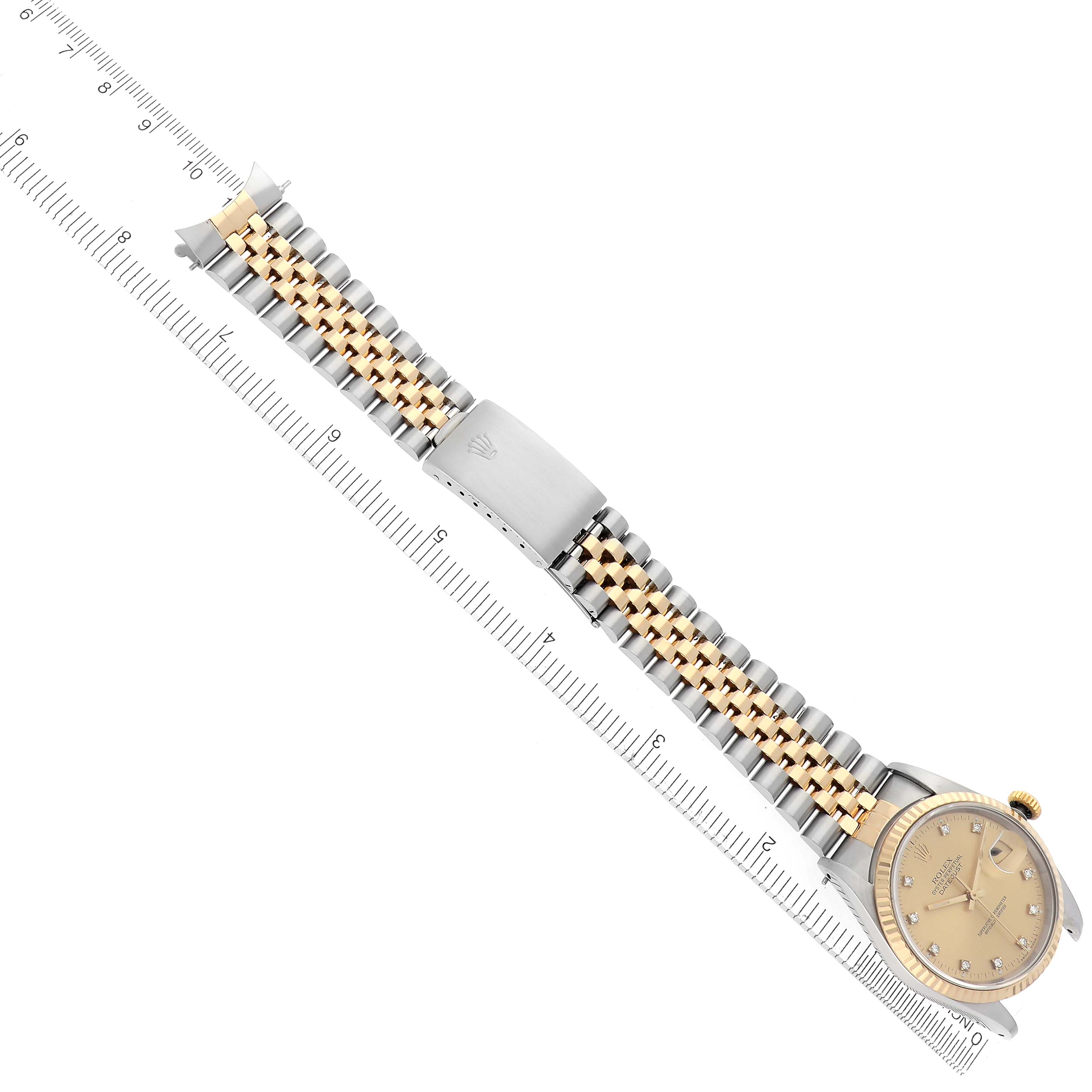 The Rolex Datejust 16233 Men's Steel and Gold (two tone) Champagne Dial 16233 Men's Steel and Gold (two tone) Champagne Dial watch is shown from an overhead angle, featuring the face, crown, and full bracelet with a ruler for scale.