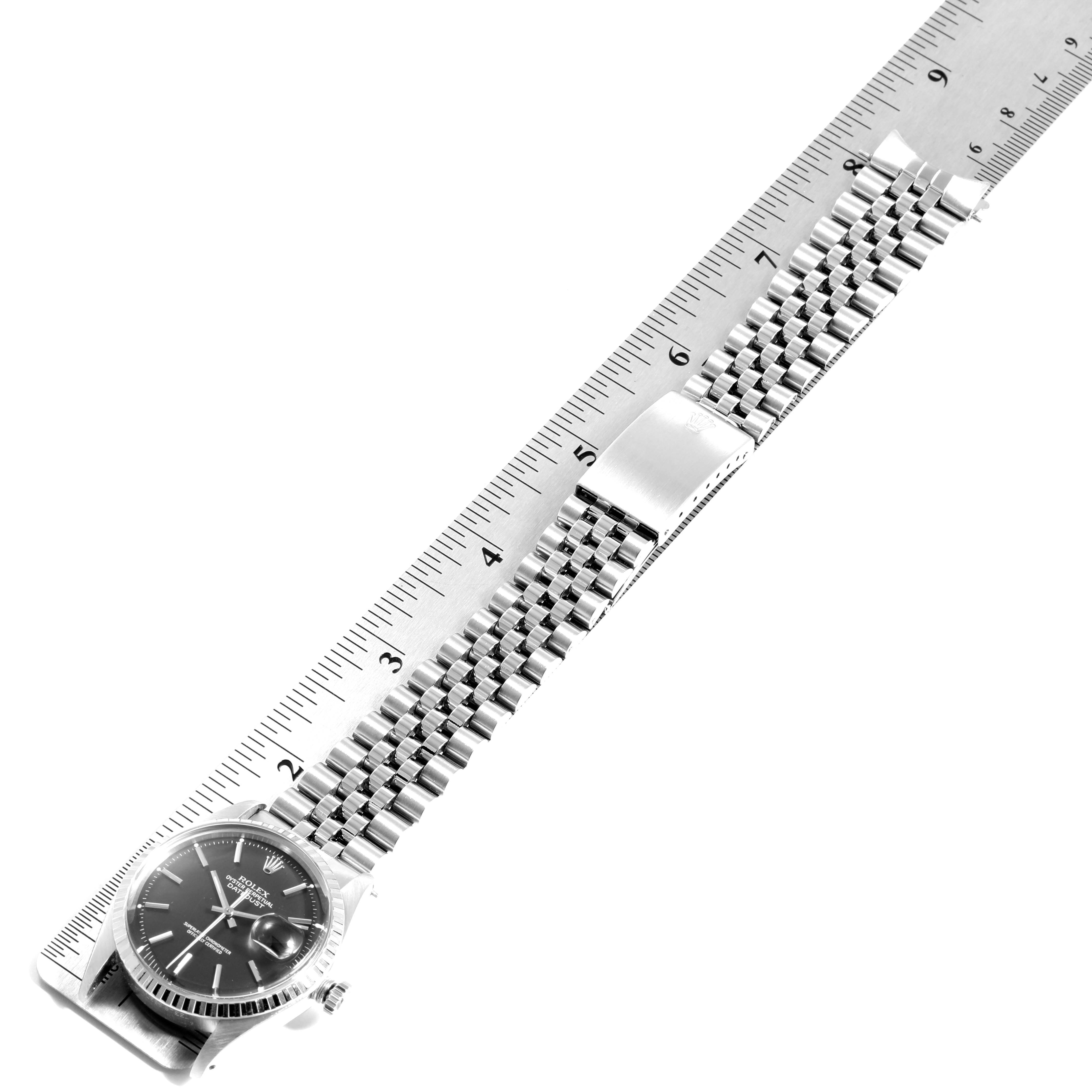 The image shows a flat-lay view of a Rolex Datejust 1603 Men's Stainless Steel Black Dial 1603 Men's Stainless Steel Black Dial watch with its full metal bracelet aligned next to a ruler.