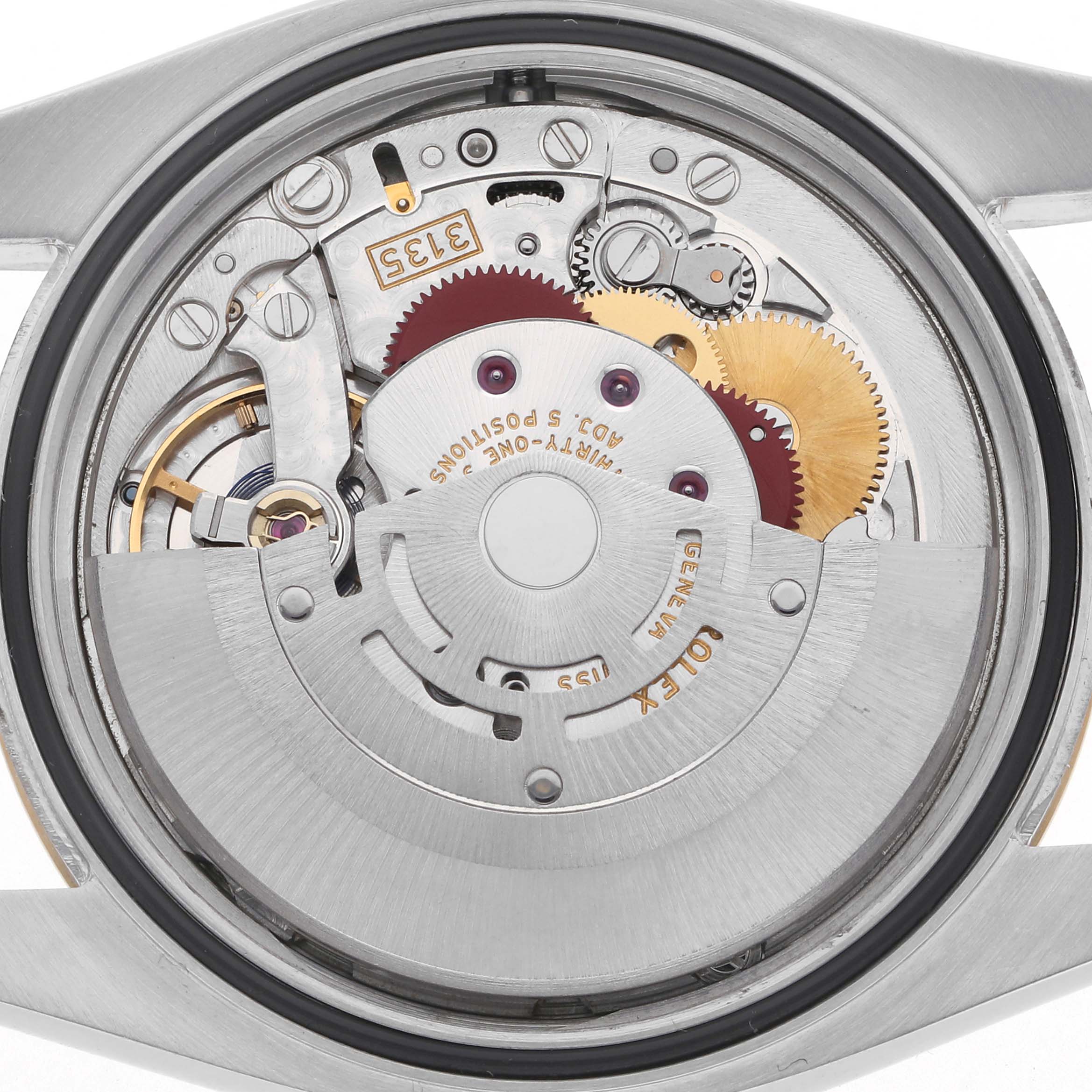 The image shows the movement of a Rolex Datejust 116233 Men's Steel and Gold (two tone) Silver Dial 116233 Men's Steel and Gold (two tone) Silver Dial watch from a rear angle, revealing gears and intricate mechanical components.