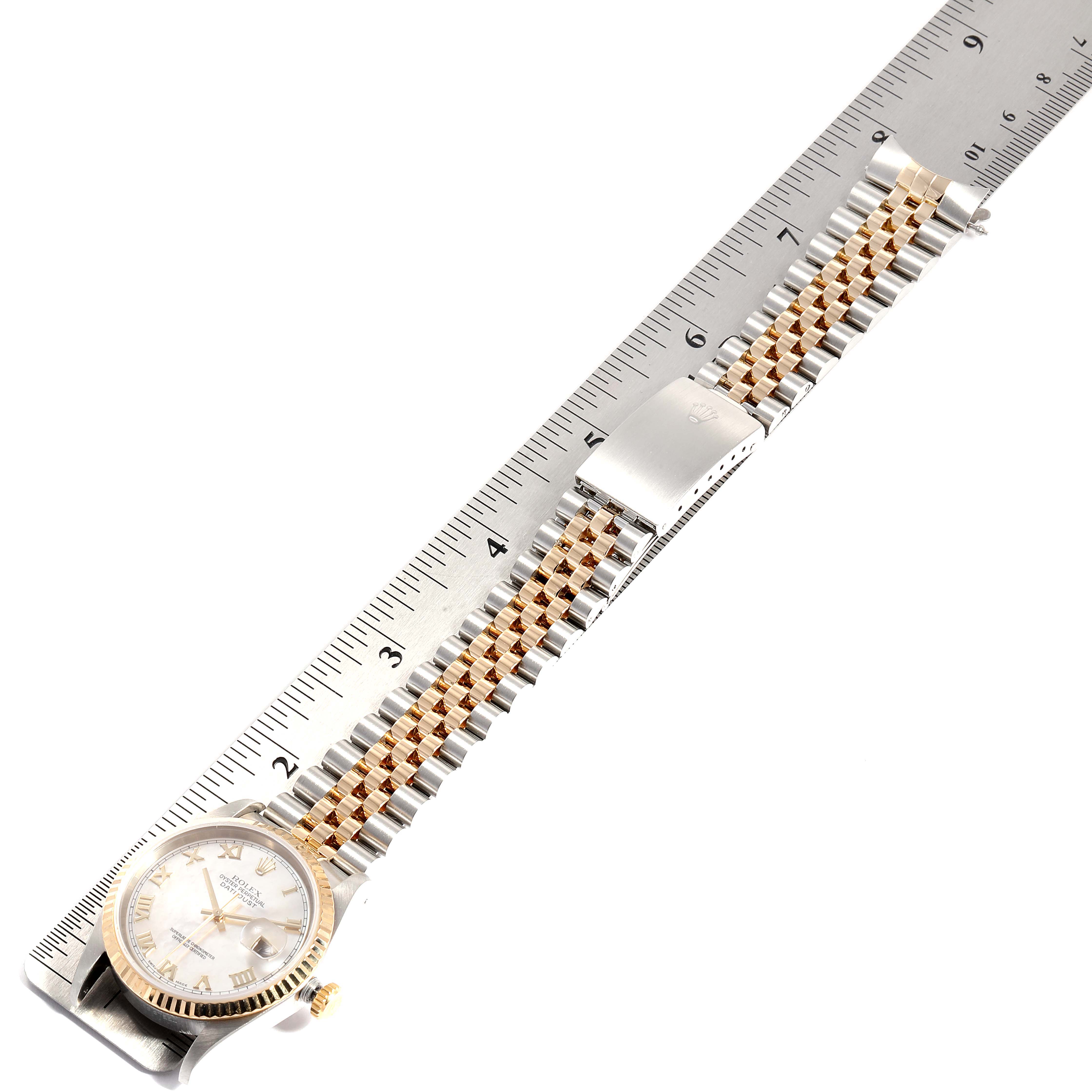 The image shows a top view of a Rolex Datejust 16233 Men
s Steel and Gold (two tone) Mother of Pearl Dial 16233 Men
s Steel and Gold (two tone) Mother of Pearl Dial watch placed next to a ruler, displaying its face, bezel, and bracelet.