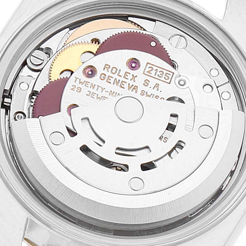 The image shows a close-up of the Rolex Datejust 69173 Women
s Steel and Gold (two tone) White Dial 69173 Women
s Steel and Gold (two tone) White Dial watch movement, featuring gears and the oscillating weight.