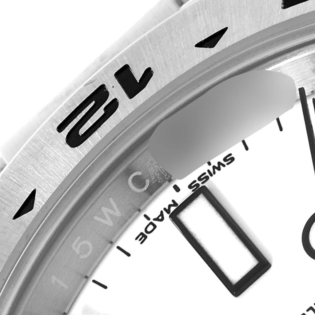 The image shows a close-up of the bezel and part of the dial of a Rolex Explorer 216570 Men
s Stainless Steel White Dial 216570 Men
s Stainless Steel White Dial watch.