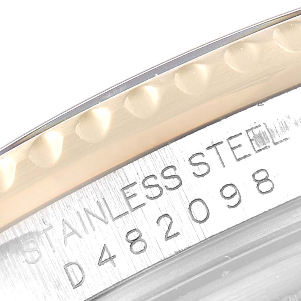 This close-up image of a Rolex GMT-Master 16713 Men's Steel and Gold (two tone) Black Dial 16713 Men's Steel and Gold (two tone) Black Dial watch shows part of the bezel edge and engraved serial numbers on the stainless steel case.