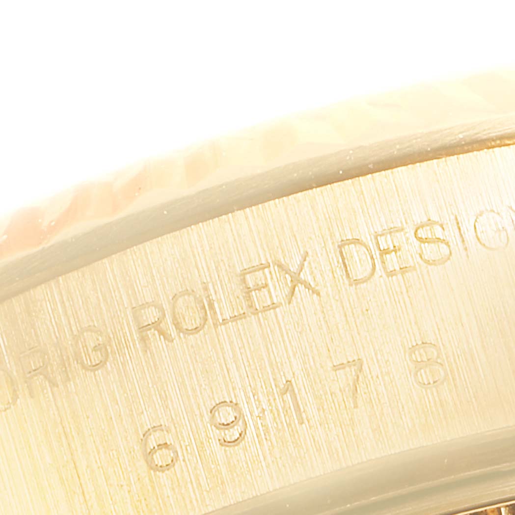 The image shows a close-up of the side of a Rolex President 69178 Women's Yellow Gold Black Dial 69178 Women's Yellow Gold Black Dial watch, focusing on the engraved text and serial number.