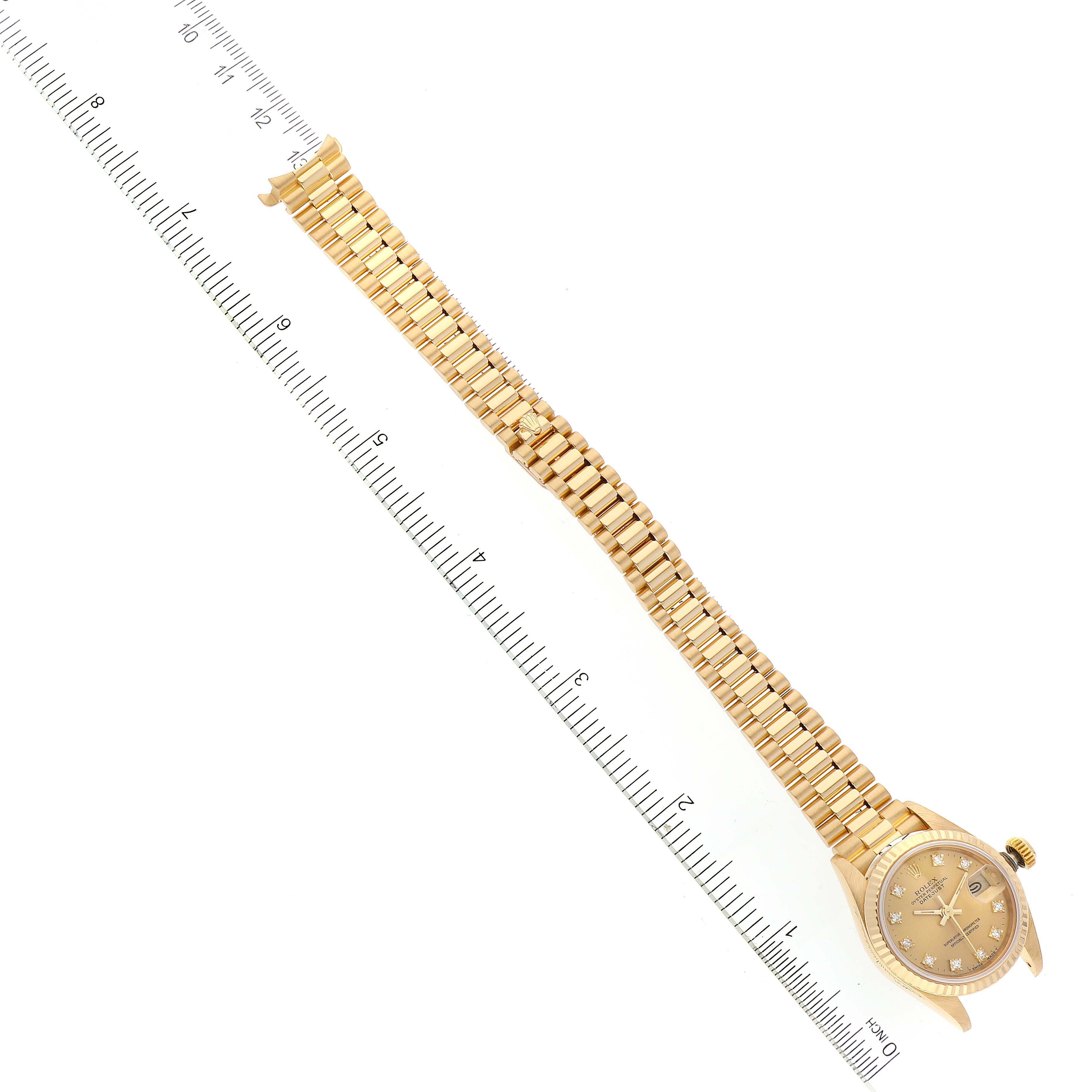 The image shows a Rolex President 69178 Women's Yellow Gold Champagne Dial 69178 Women's Yellow Gold Champagne Dial model watch laid flat with its face and full bracelet visible alongside a ruler for scale.
