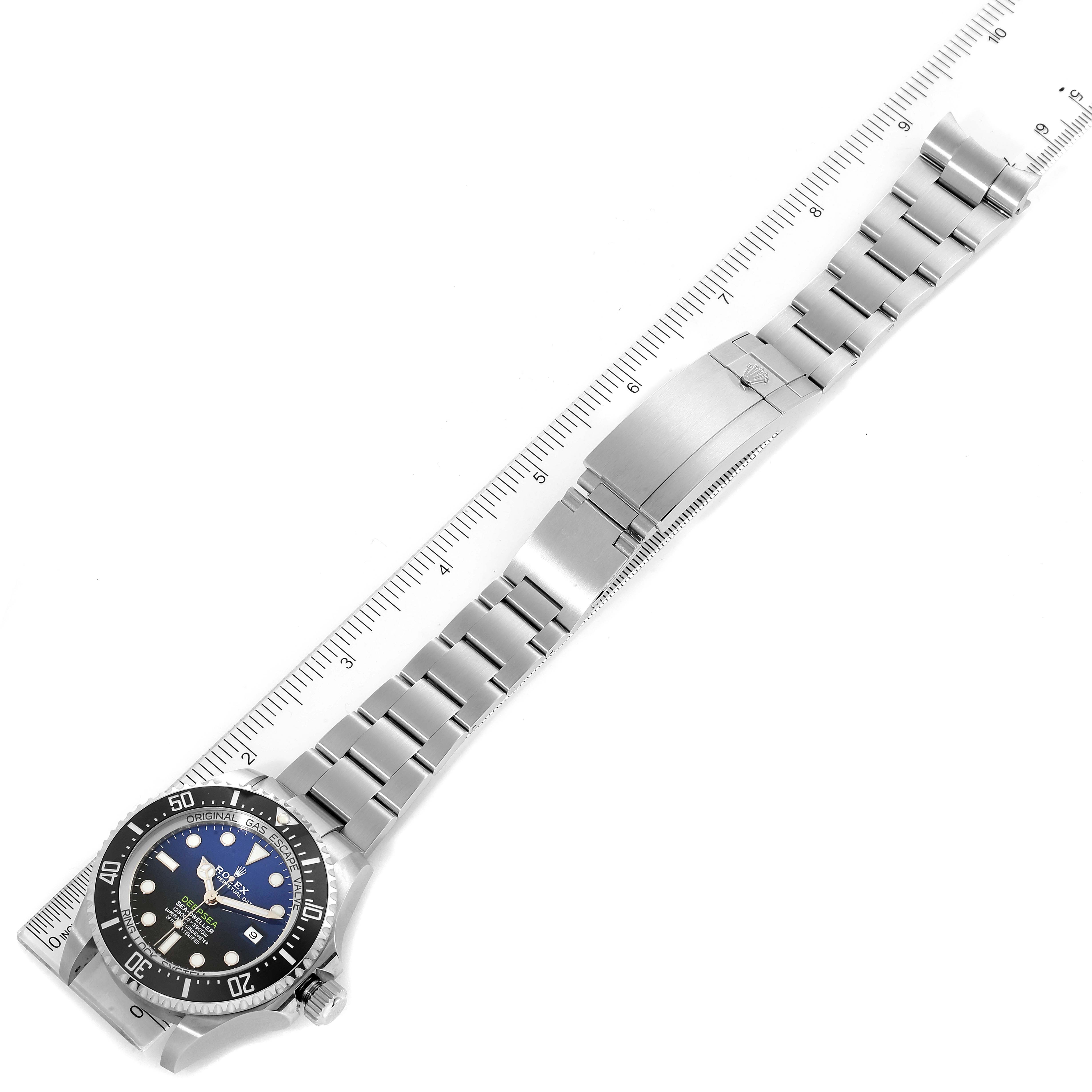 The image shows a top view of a Rolex Sea-Dweller 126660 Men
s Stainless Steel Blue Dial 126660 Men
s Stainless Steel Blue Dial watch, including its stainless steel bracelet and clasp, alongside a ruler.