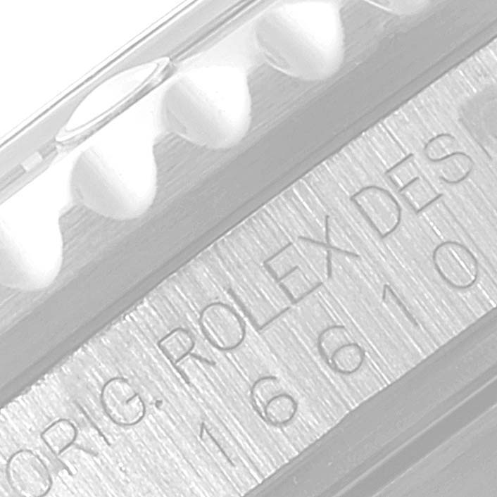 The image shows an angled close-up of the Rolex Submariner 16610 Men
s Stainless Steel Black Dial 16610 Men
s Stainless Steel Black Dial model
s engraving and part of its bezel.