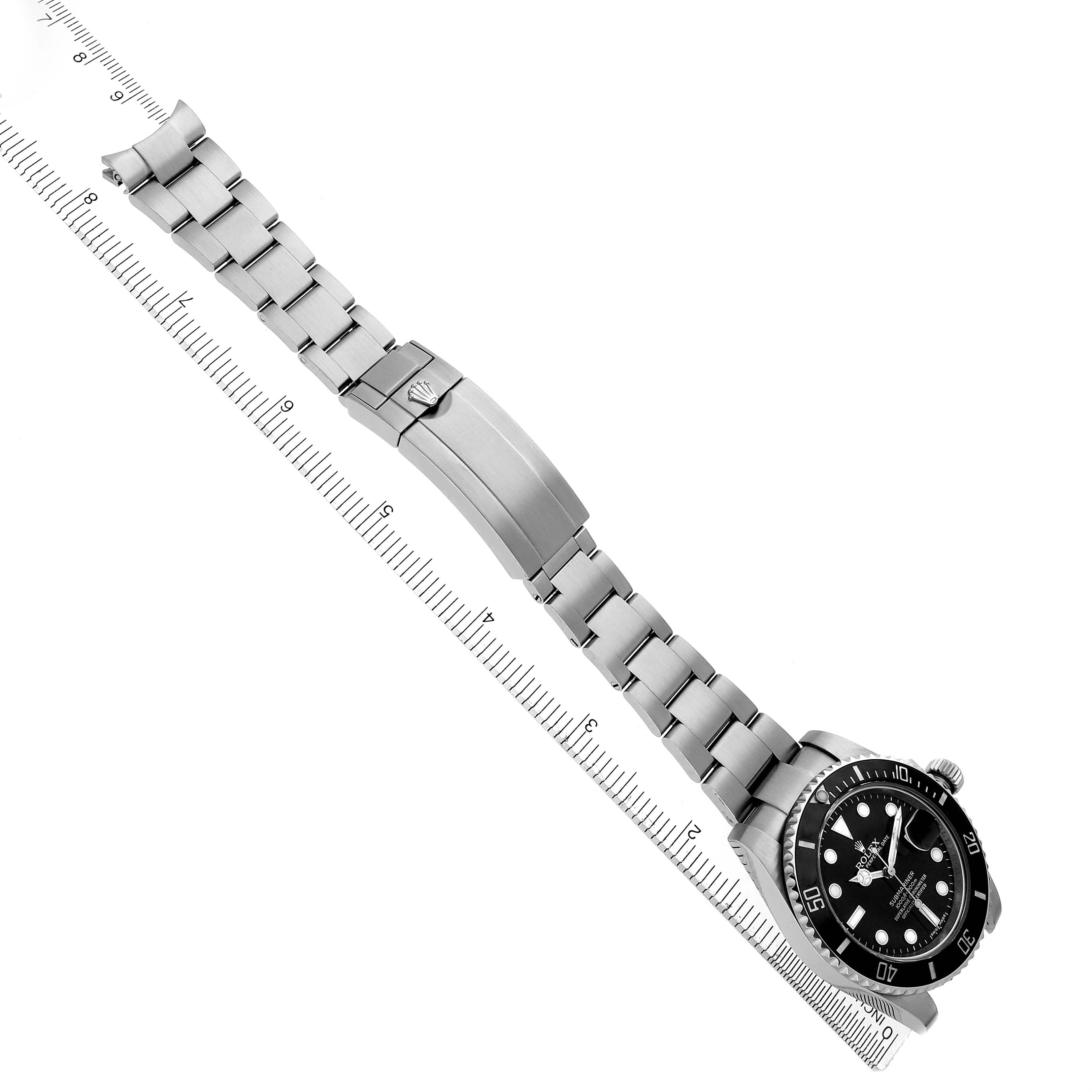 The Rolex Submariner 116610 Men's Stainless Steel Black Dial 116610 Men's Stainless Steel Black Dial watch is shown from a top-down angle, showcasing its face, bracelet, and clasp alongside a ruler.