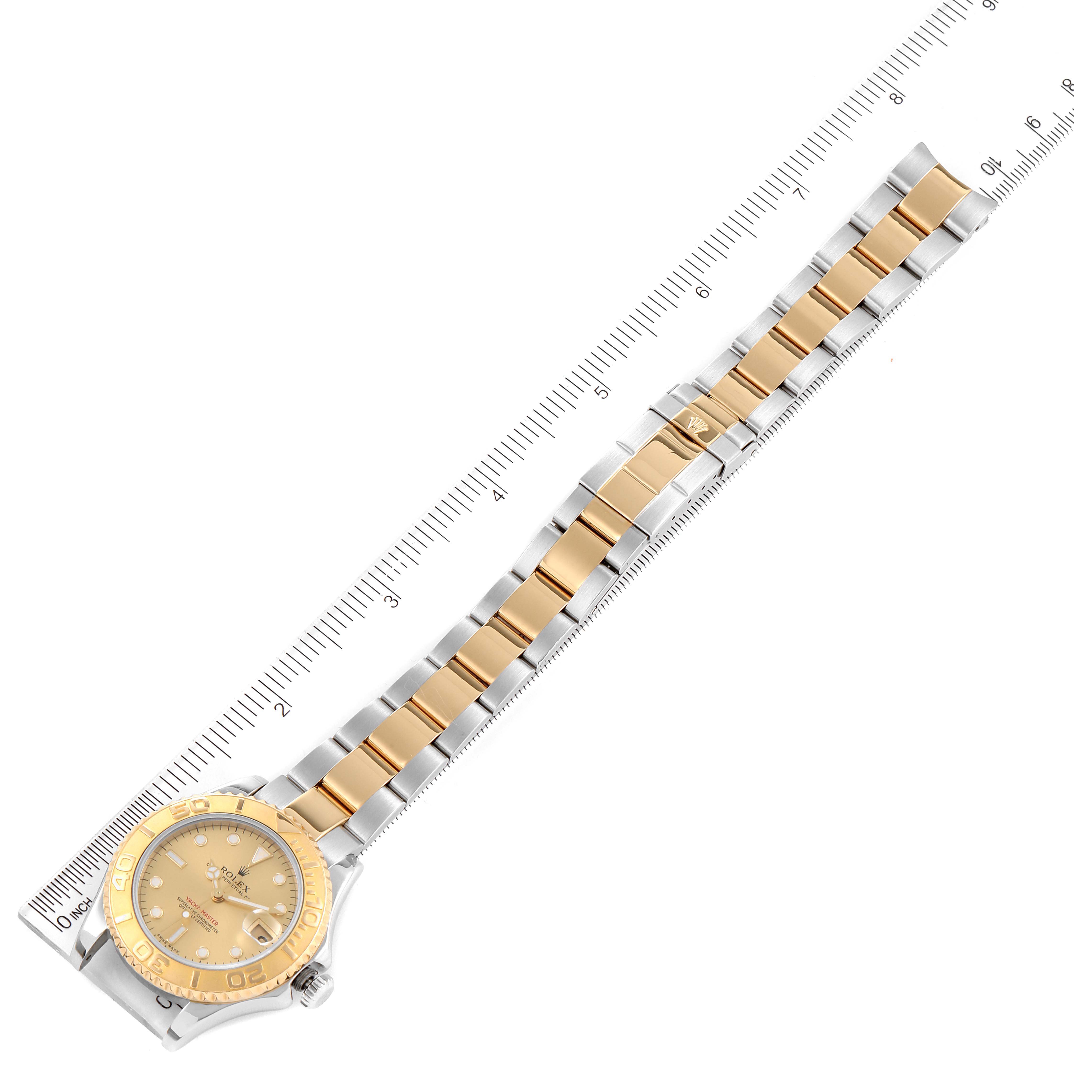 The Rolex Yacht-Master 68623 Men
s Steel and Gold (two tone) Champagne Dial 68623 Men
s Steel and Gold (two tone) Champagne Dial watch is shown laid flat with a ruler, displaying the face, bezel, and full bracelet with gold and silver links.