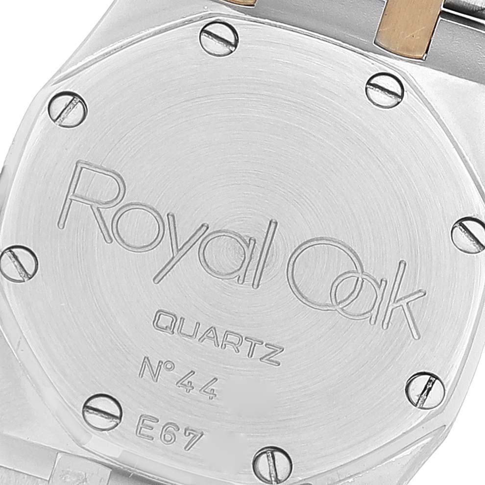 The image shows the back plate of an Audemars Piguet Royal Oak Women's Steel and Gold (two tone) Grey Dial Women's Steel and Gold (two tone) Grey Dial Quartz watch, featuring engraved text and screws.