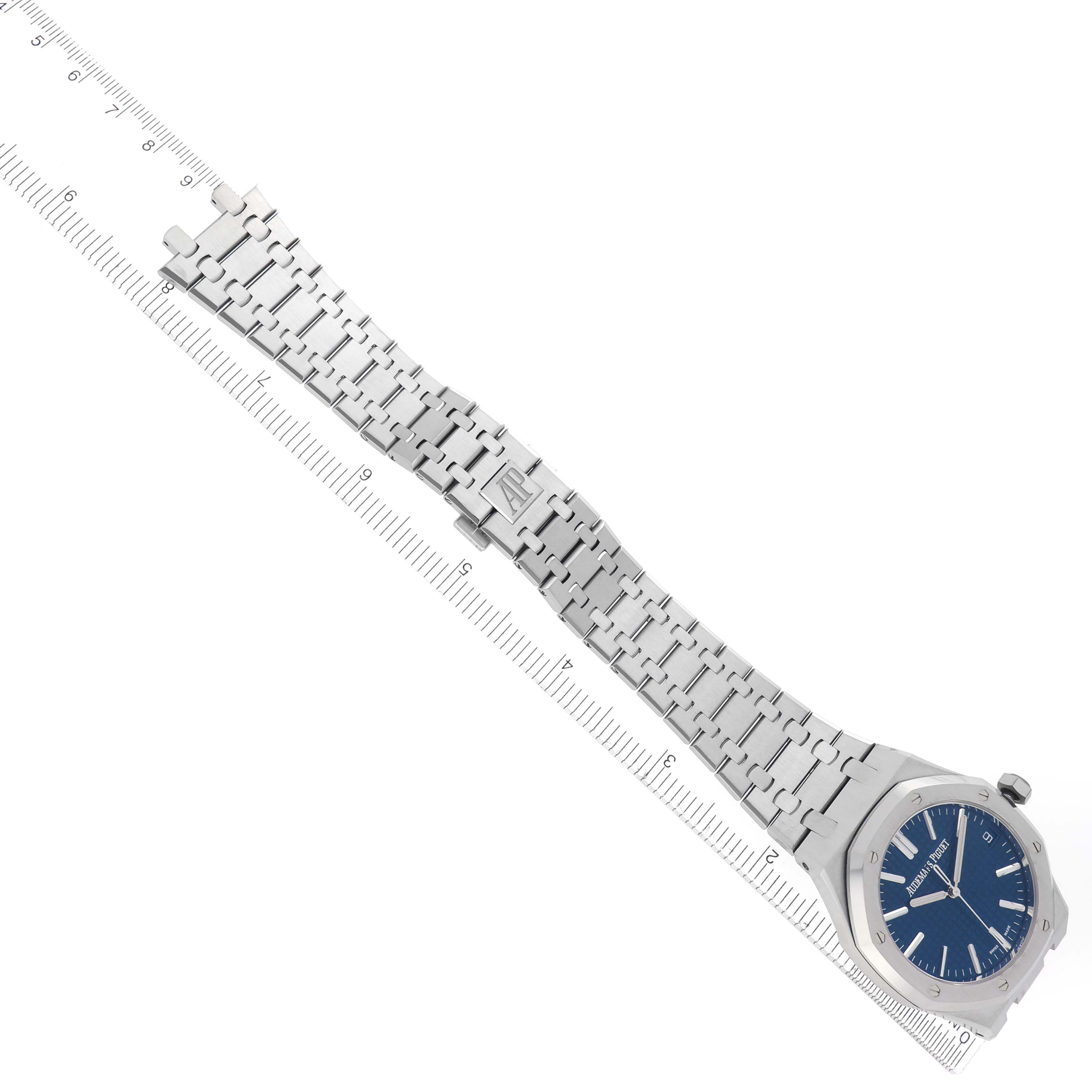 The image shows an Audemars Piguet Royal Oak 15500ST.OO.1220ST.01 Men's Stainless Steel Blue Dial 15500ST.OO.1220ST.01 Men's Stainless Steel Blue Dial watch, angled to display its blue dial and metal bracelet alongside a ruler.
