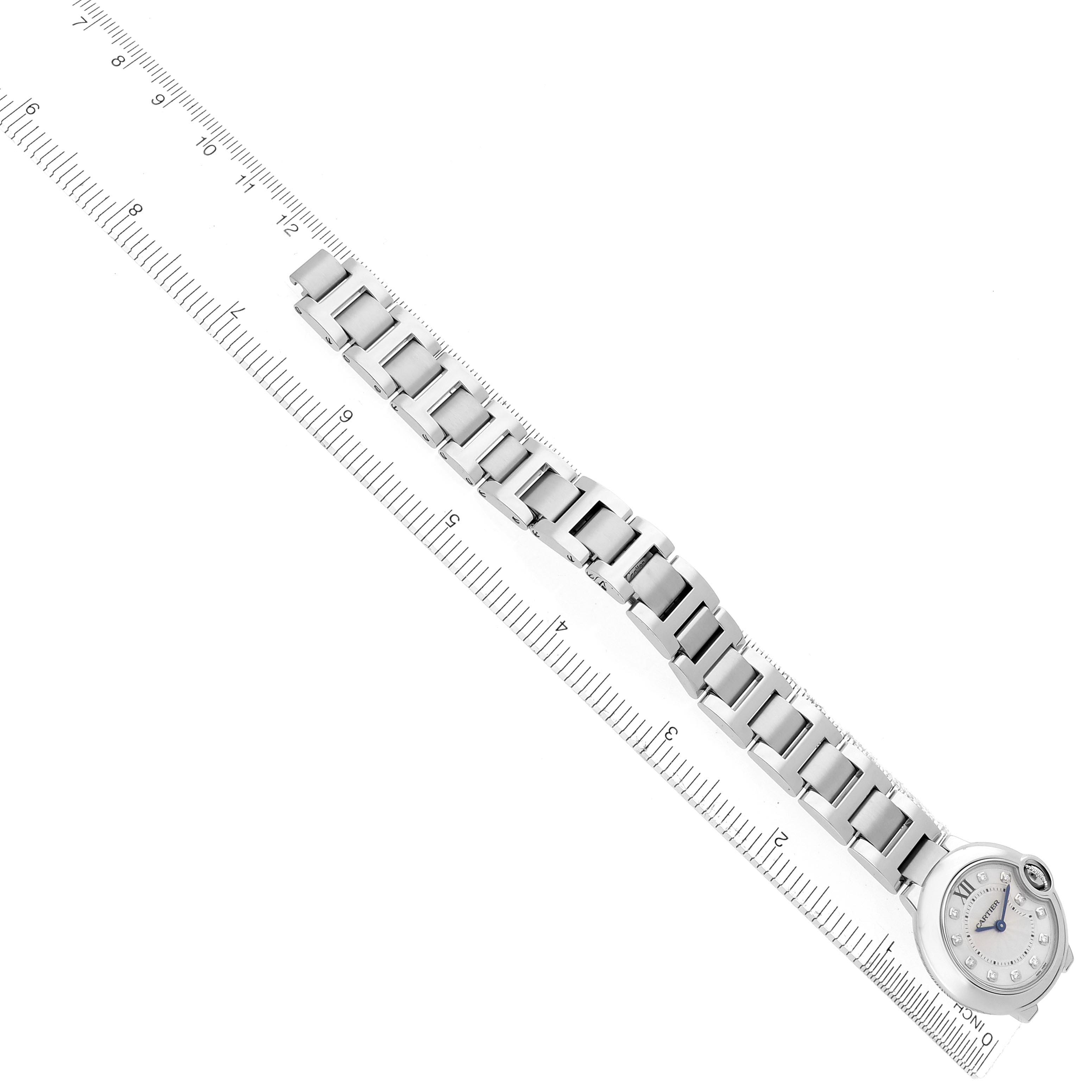 The Ballon Bleu by Cartier is displayed from a top-down angle, showing the entire watch bracelet and face alongside a ruler.