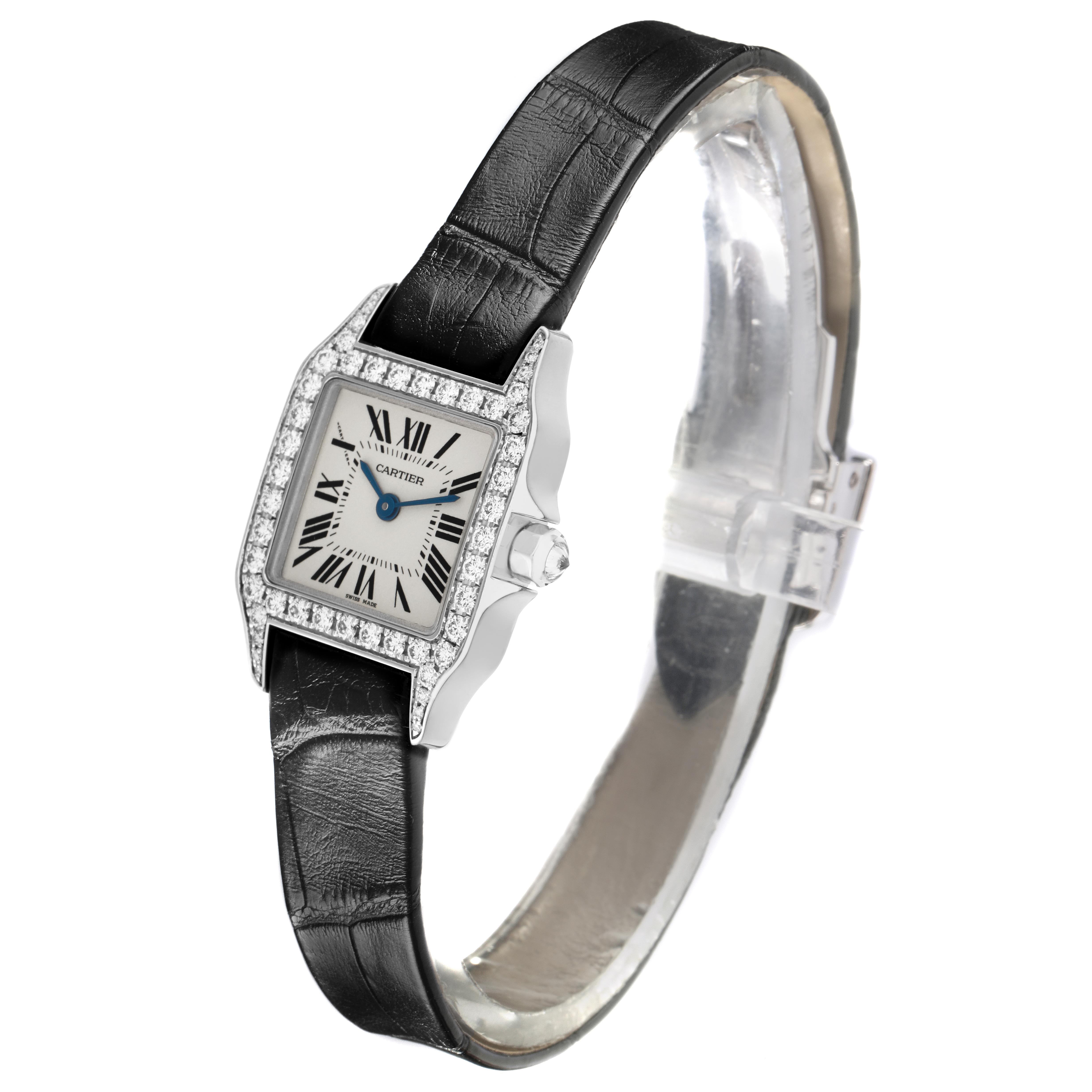 The Cartier Santos Demoiselle WF9005Y8 Women's White Gold Silver Dial WF9005Y8 Women's White Gold Silver Dial watch is shown at a three-quarter angle, highlighting its rectangular face, diamond bezel, and black strap.