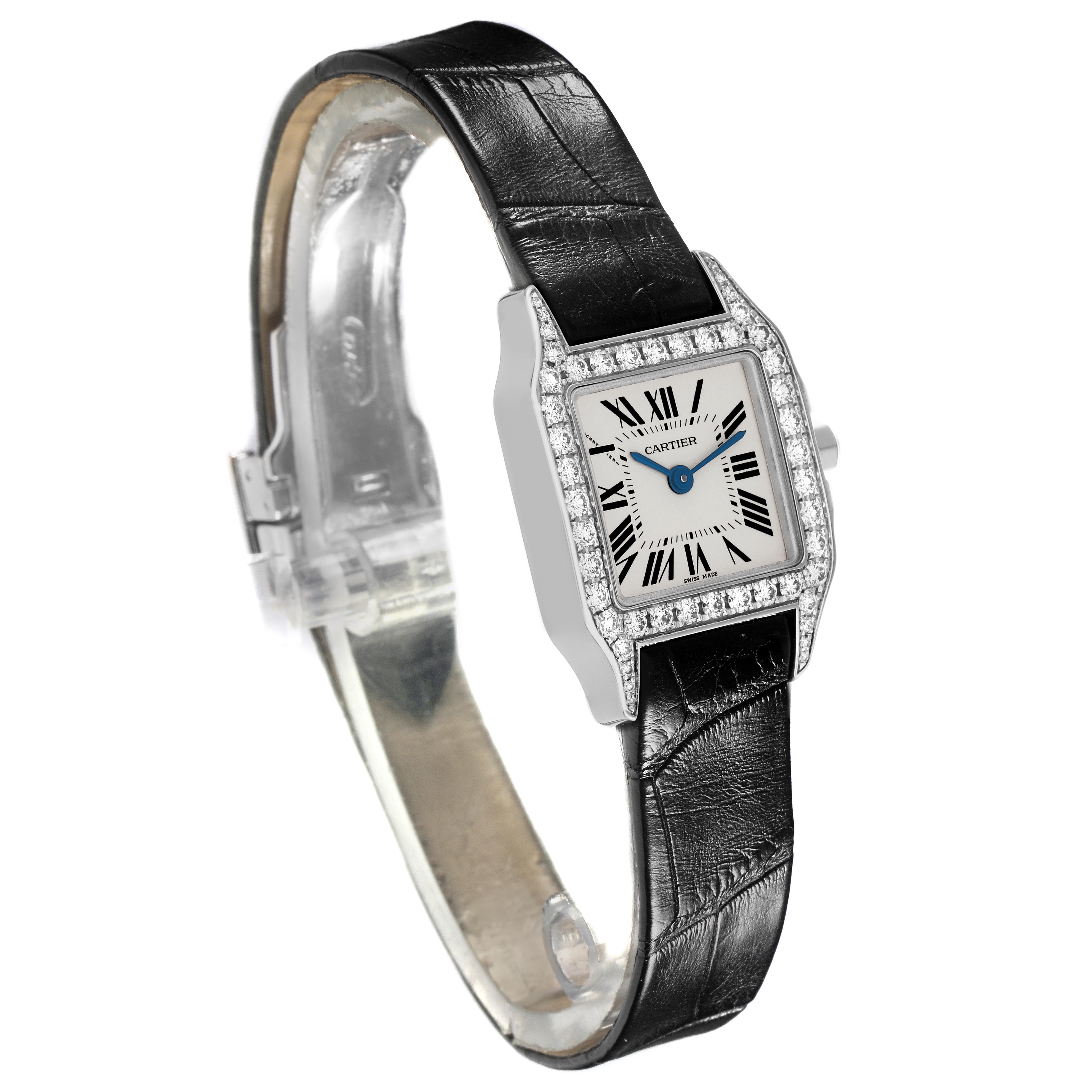 The Cartier Santos Demoiselle WF9005Y8 Women's White Gold Silver Dial WF9005Y8 Women's White Gold Silver Dial watch is shown from a three-quarter angle, highlighting its diamond-studded bezel, dial, and leather strap.