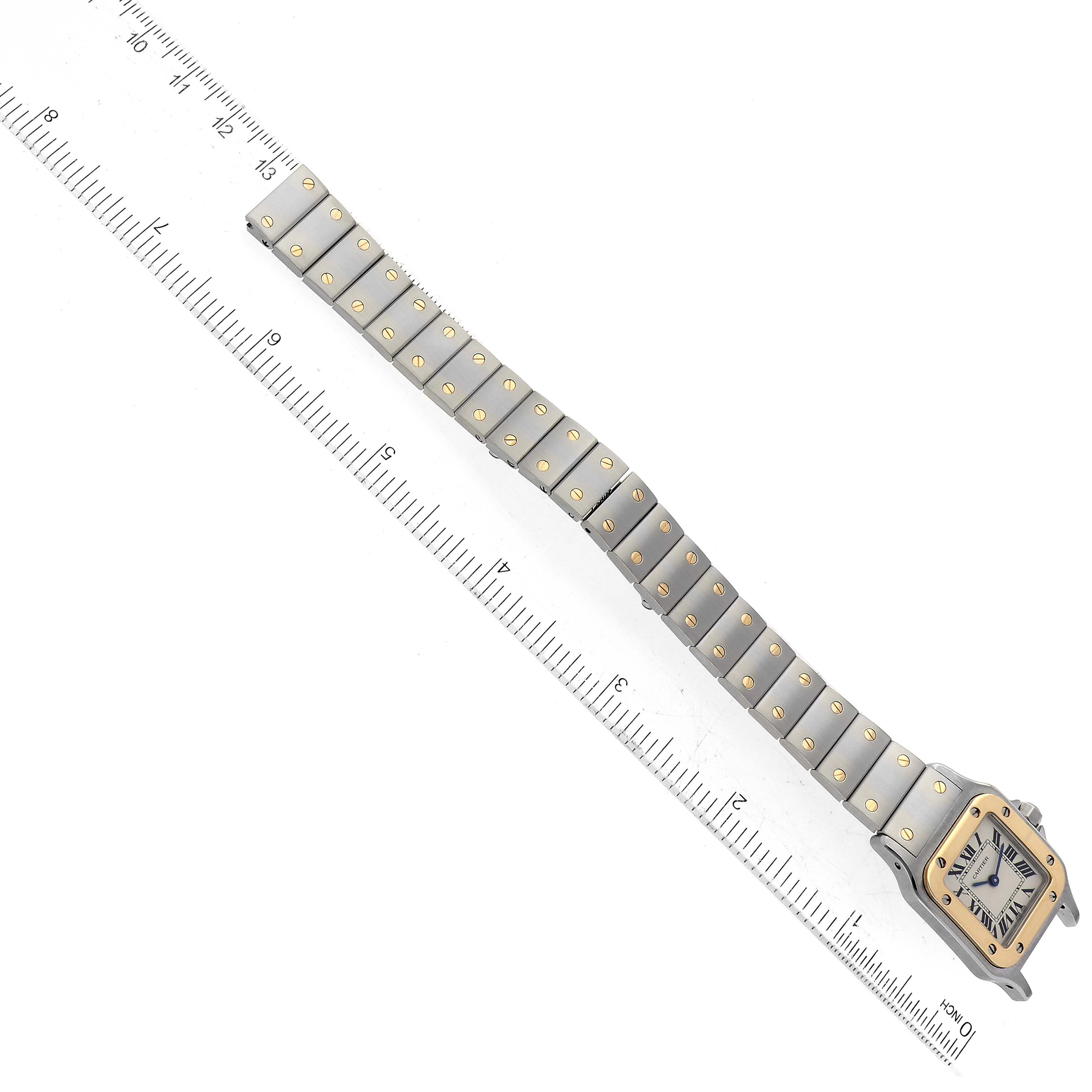This image shows a Cartier Santos W20012C4 Women's Steel and Gold (two tone) Silver Dial W20012C4 Women's Steel and Gold (two tone) Silver Dial watch laid flat at a slight angle, next to a ruler for size reference.
