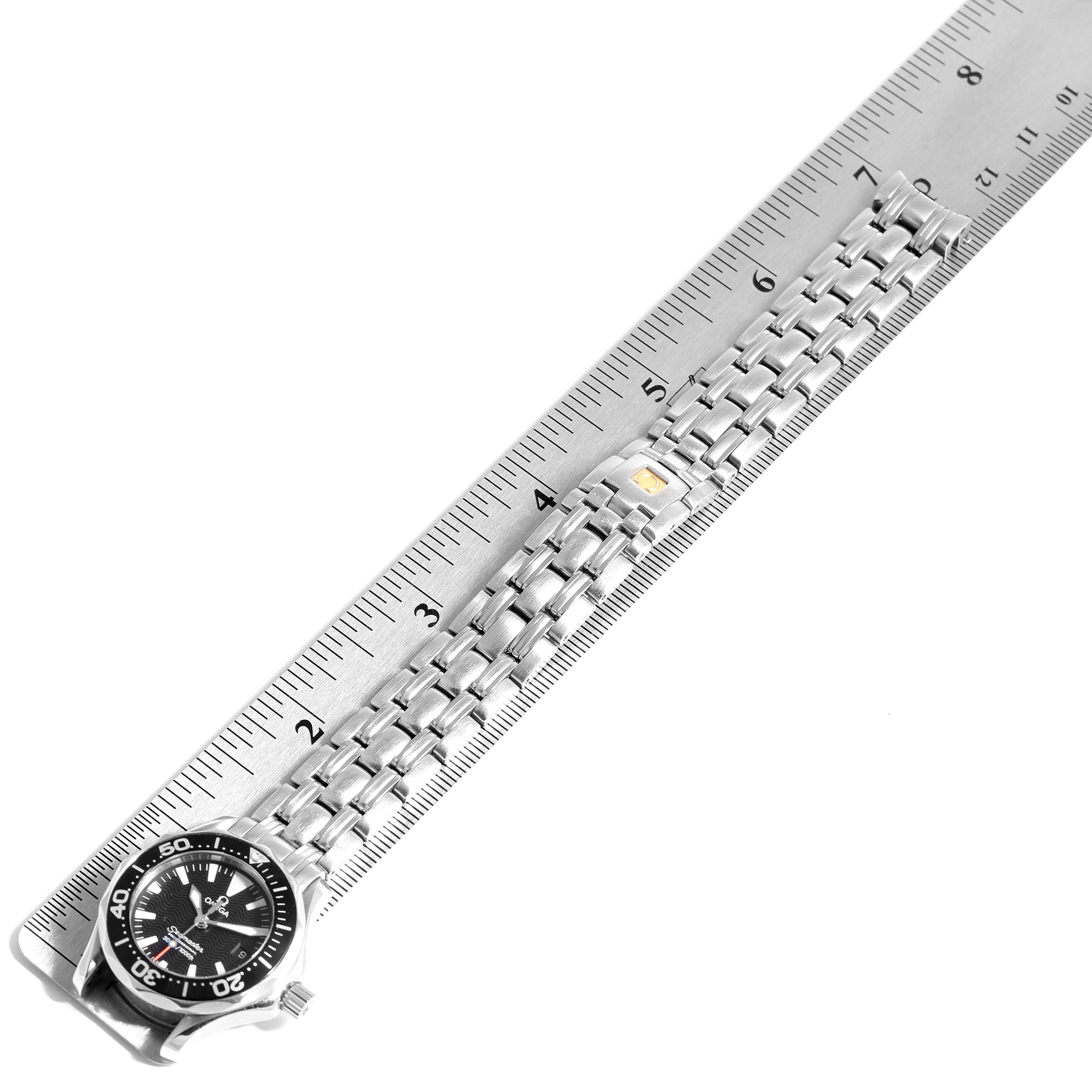 The Omega 2284.50.00 Women's Stainless Steel Black Dial 2284.50.00 Women's Stainless Steel Black Dial Seamaster Diver 300M Quartz 28mm Steel Ladies Watch 2284.50.00 is shown from an overhead angle, highlighting its face and bracelet against a ruler.