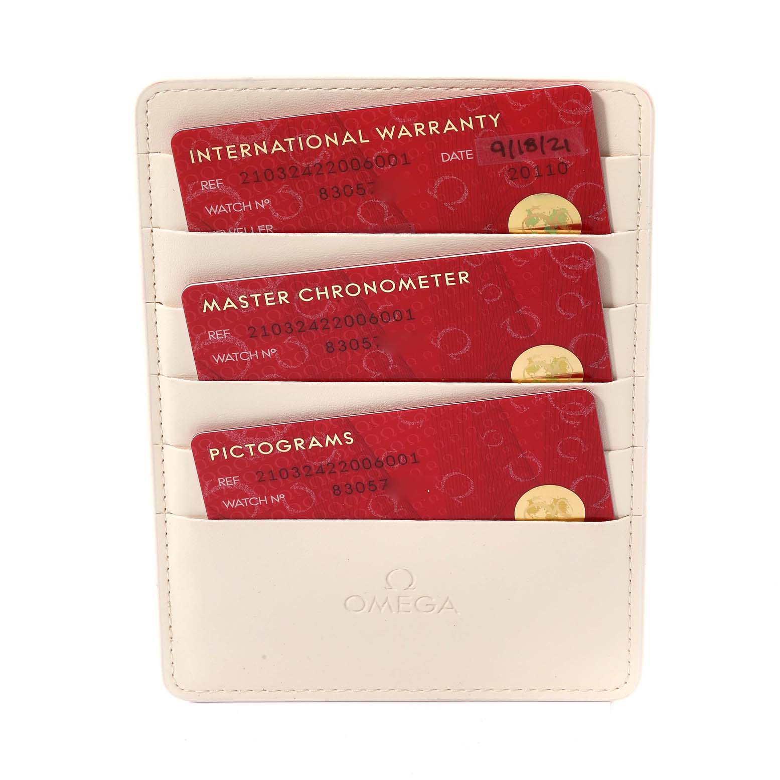 The image shows three warranty cards in a white Omega holder, including the Aquaterra Seamaster model by Omega.