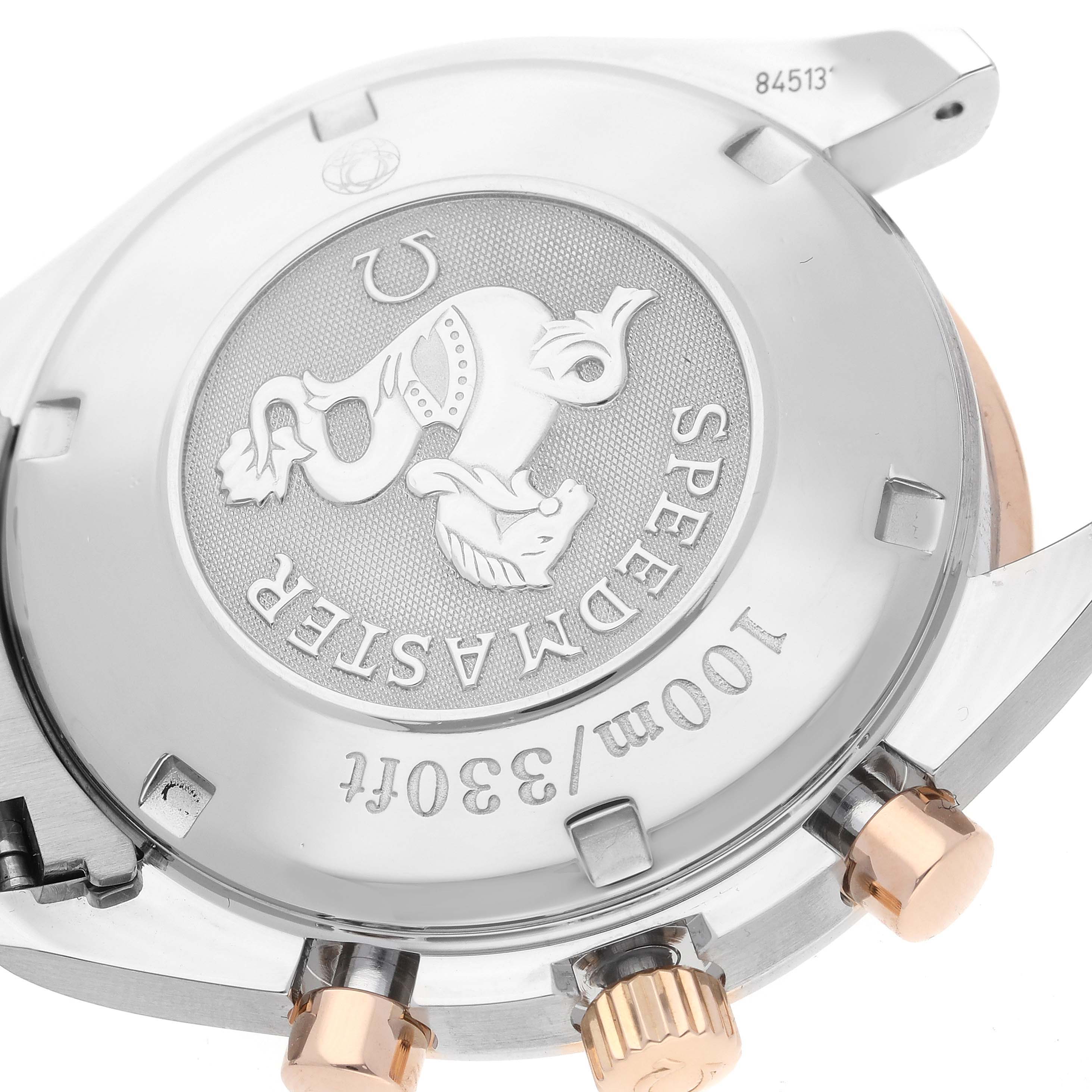 This is a close-up view of the case back of an Omega Speedmaster 323.21.40.44.01.001 Men's Steel and Gold (two tone) Black Dial 323.21.40.44.01.001 Men's Steel and Gold (two tone) Black Dial watch, highlighting the engraved emblem and text.