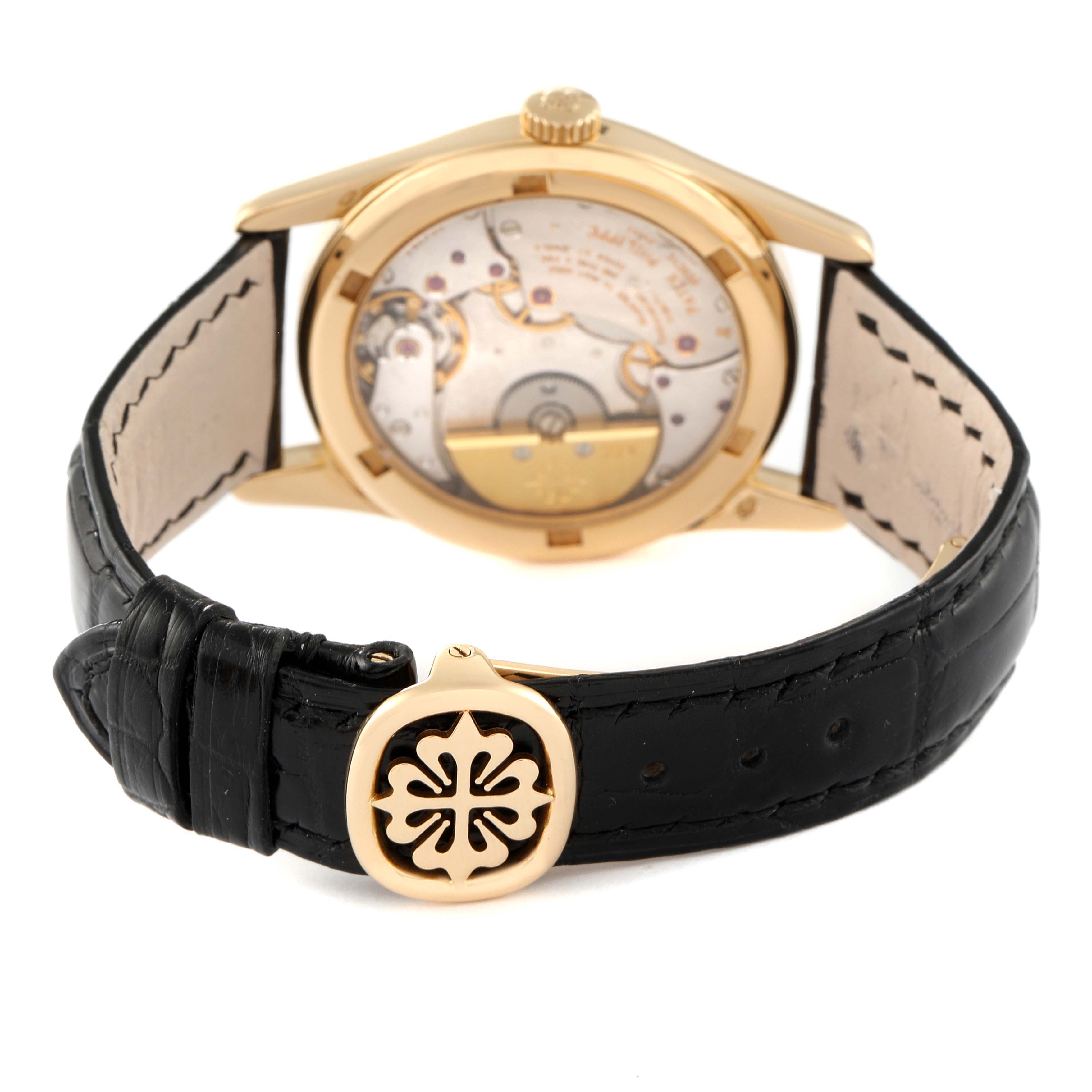 The image shows the back view of a Patek Philippe Calatrava 5000J Men's Yellow Gold Black Dial 5000J Men's Yellow Gold Black Dial watch, highlighting its movement and leather strap with a logo clasp.