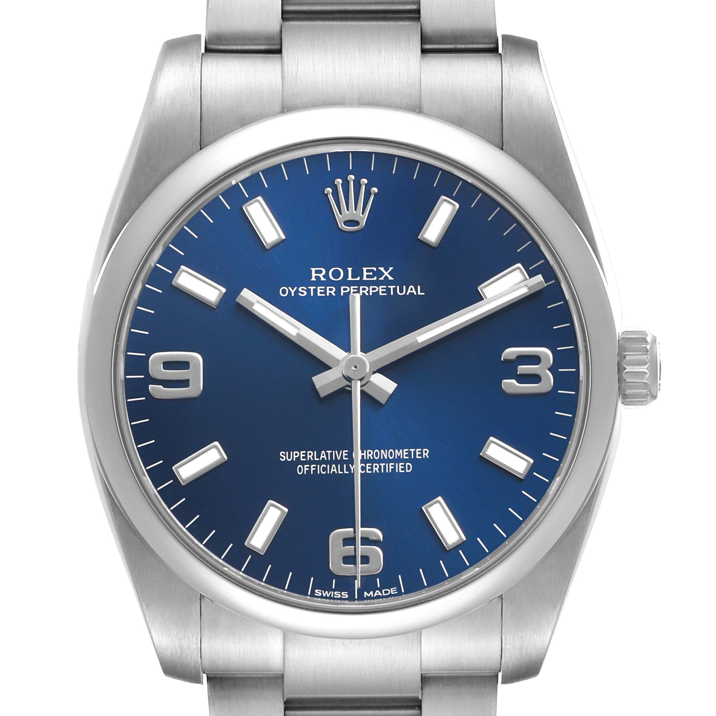 The Rolex Oyster Perpetual 114200 Men's Stainless Steel Blue Dial watch is shown from the front, displaying its blue dial, indices, hands, and part of the stainless steel bracelet.