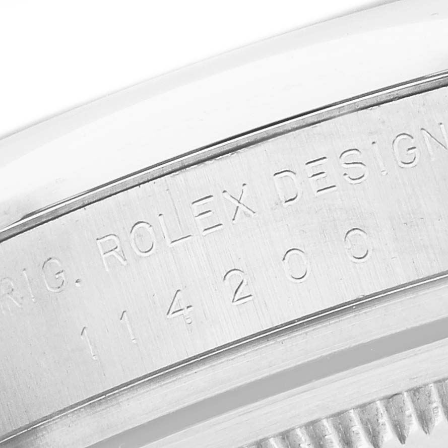 The image shows the side engraving on the caseback of a Rolex Oyster Perpetual 114200 Men's Stainless Steel Blue Dial watch.