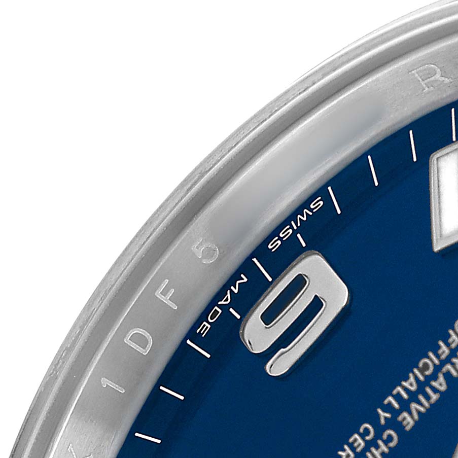 The image shows a close-up of the dial and bezel of a Rolex Oyster Perpetual 114200 Men's Stainless Steel Blue Dial watch, highlighting the "9" hour mark and "SWISS MADE" text.