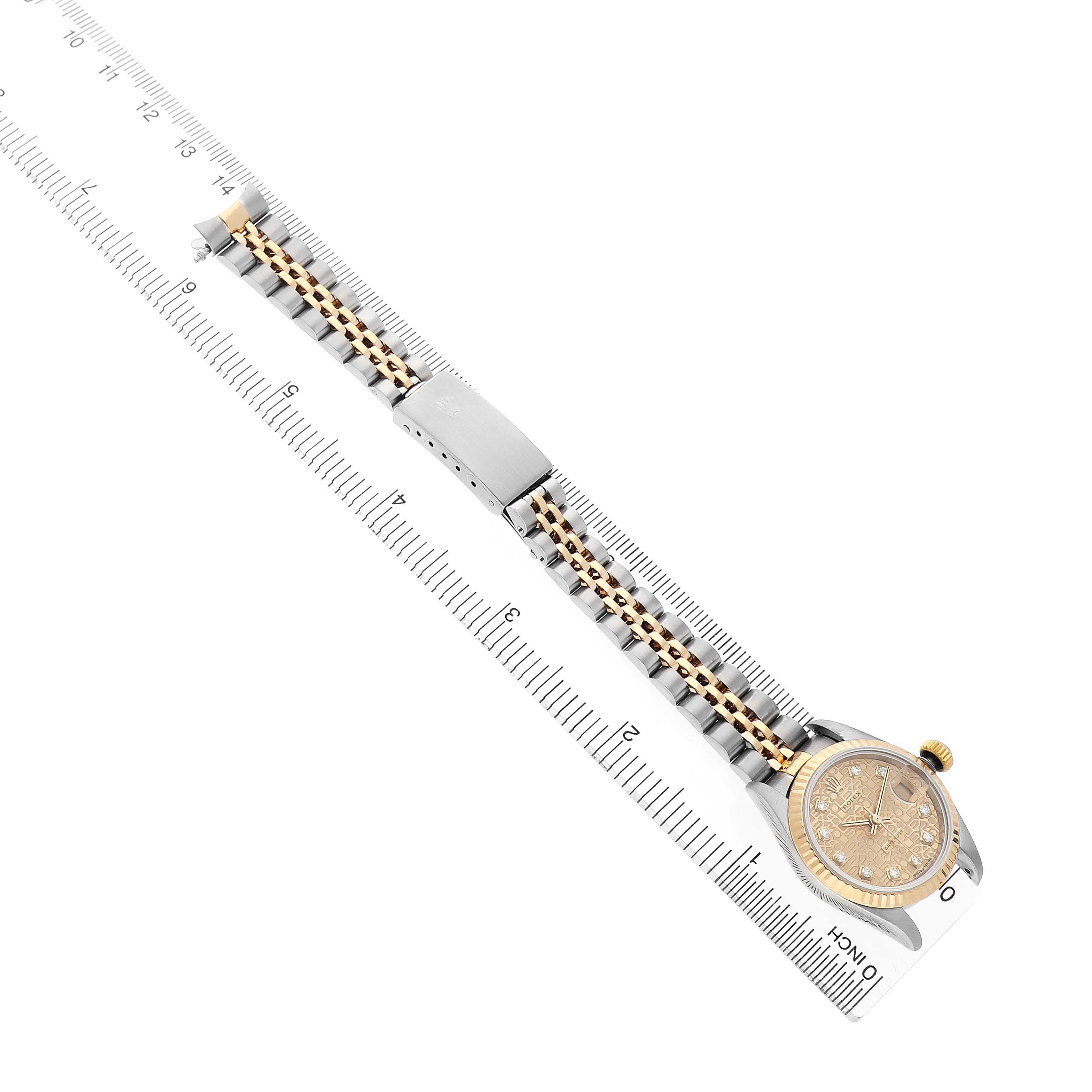 The Rolex Datejust 69173 Women's Steel and Gold (two tone) Champagne Dial watch is shown from a top view, highlighting the face, bracelet, and clasp, aligned with a ruler.