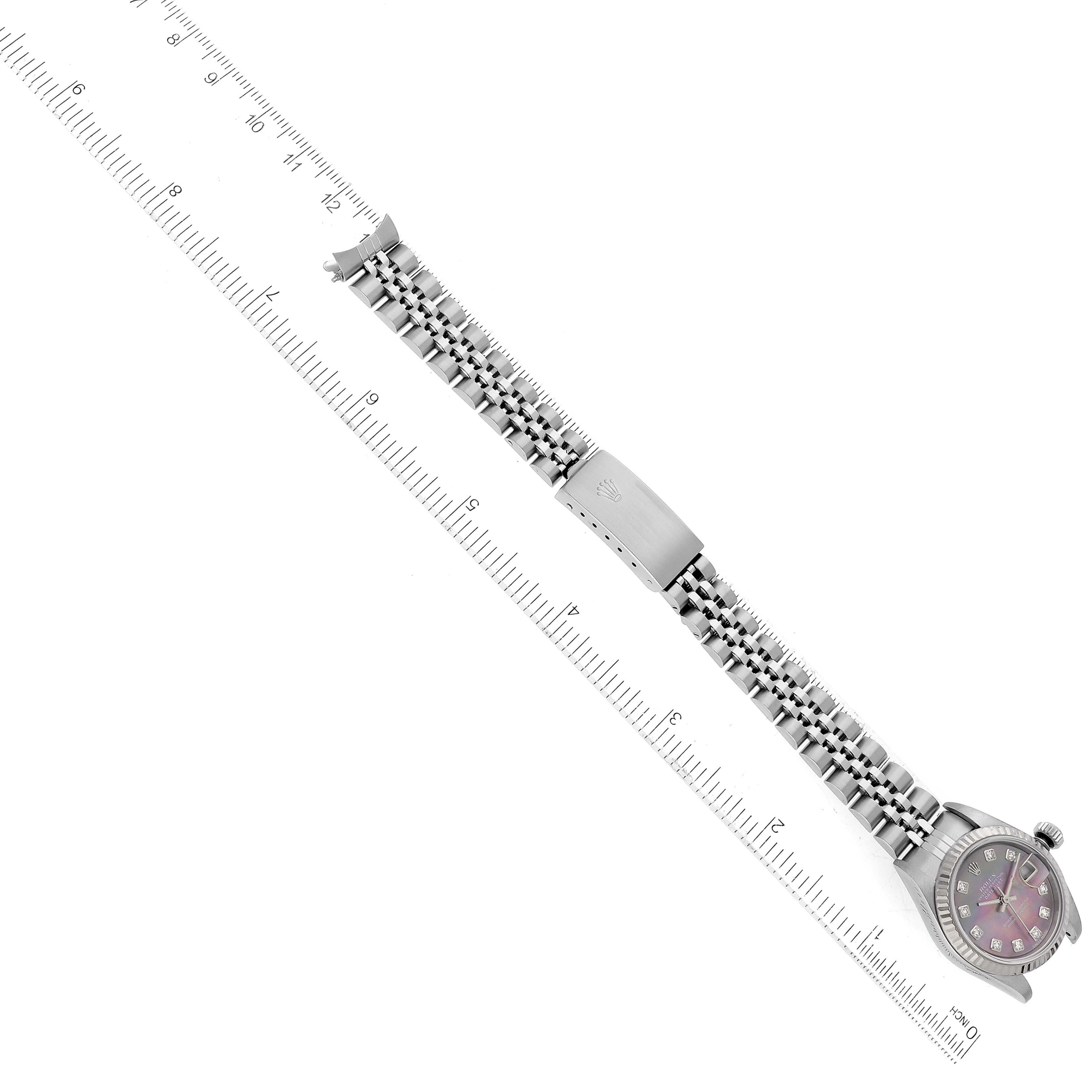 The image shows a Rolex Datejust 179174 Women
s Stainless Steel Mother of Pearl Dial 179174 Women
s Stainless Steel Mother of Pearl Dial watch, displaying the bracelet and clasp laid flat on a ruled surface for scale measurement.