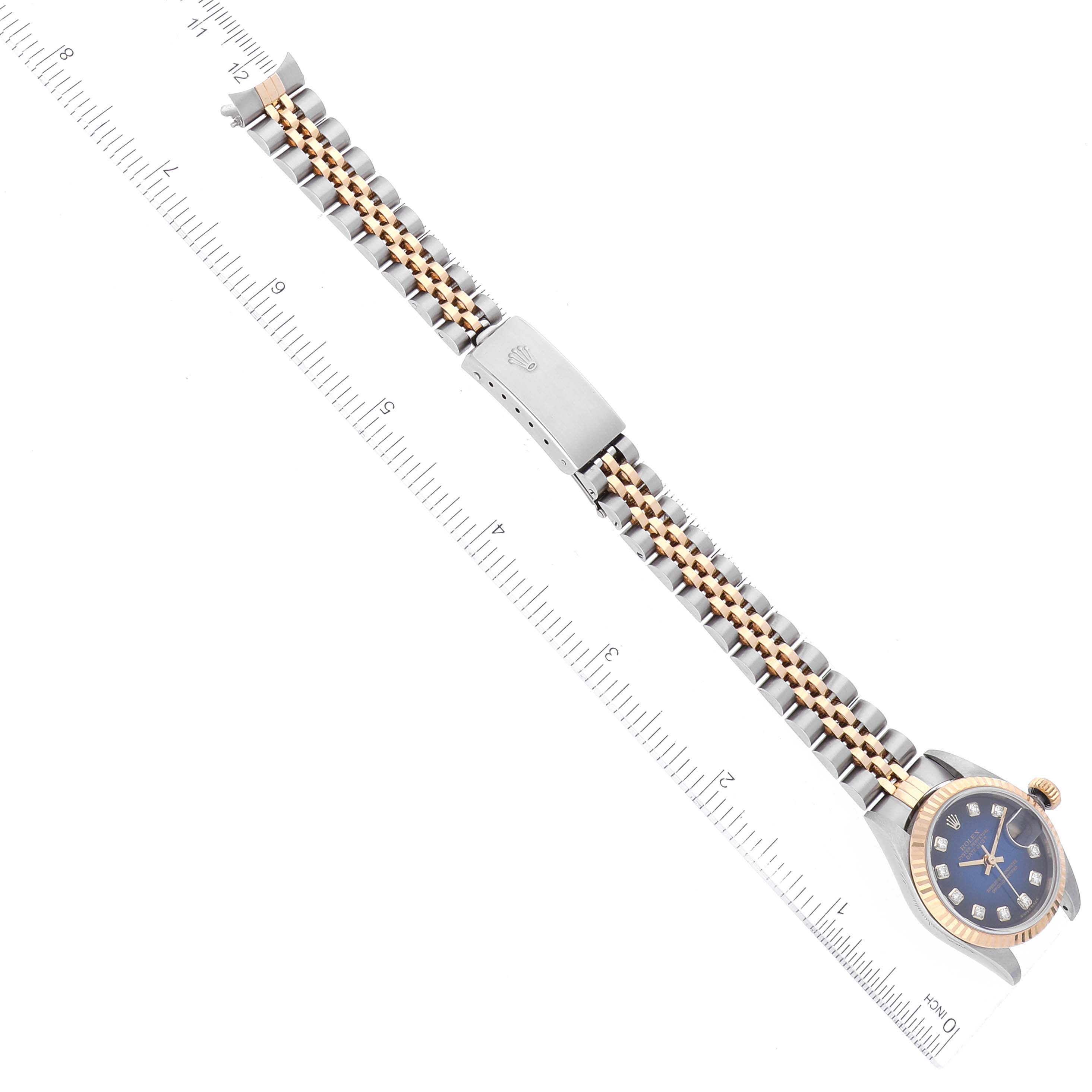The image shows a Rolex Datejust 79173 Women's Steel and Gold (two tone) Blue Dial 79173 Women's Steel and Gold (two tone) Blue Dial watch with its face, bezel, and bracelet fully extended and aligned with a ruler.