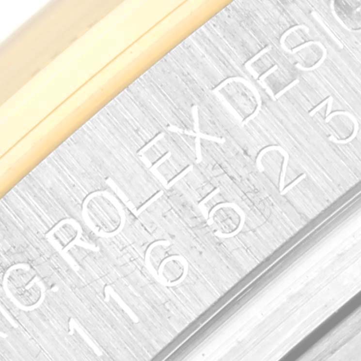 Close-up of the case edge on a Rolex Daytona 116523 Men
s Steel and Gold (two tone) Black Dial 116523 Men
s Steel and Gold (two tone) Black Dial watch showing engraved text.