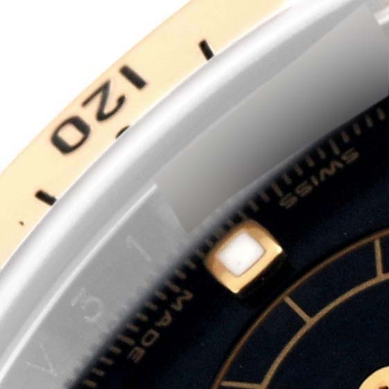 The image shows a close-up of the bezel and part of the dial with a marker of a Rolex Daytona 116523 Men
s Steel and Gold (two tone) Black Dial 116523 Men
s Steel and Gold (two tone) Black Dial watch.