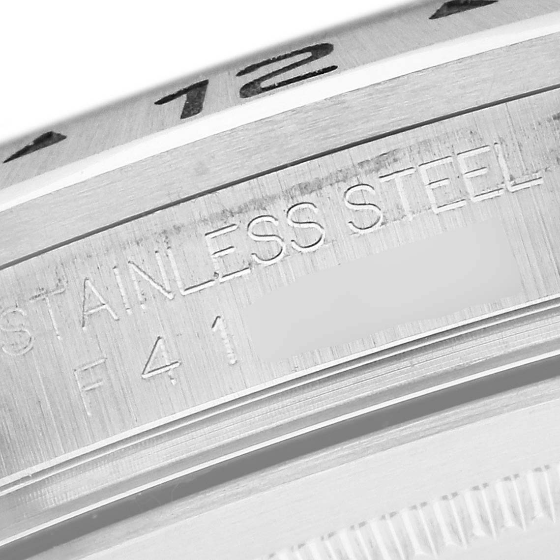 This is an extreme close-up of the side of a Rolex Explorer 16570 Men's Stainless Steel White Dial 16570 Men's Stainless Steel White Dial watch, showing engraved text and part of the bezel.