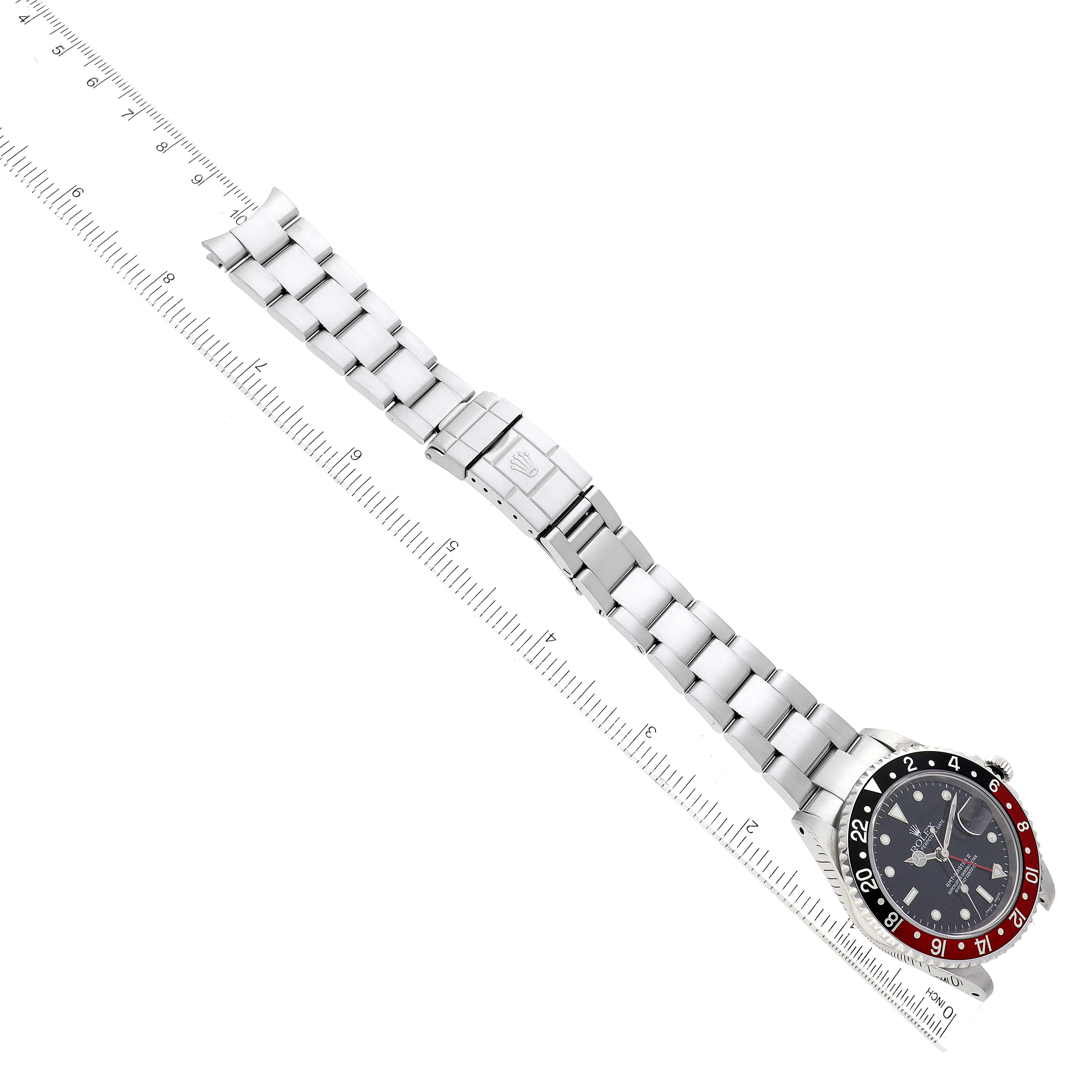 This image shows a top-down view of a Rolex GMT-Master 16710 Men
s Stainless Steel Black Dial 16710 Men
s Stainless Steel Black Dial watch, displaying the full bracelet, clasp, and face alongside a measurement ruler.