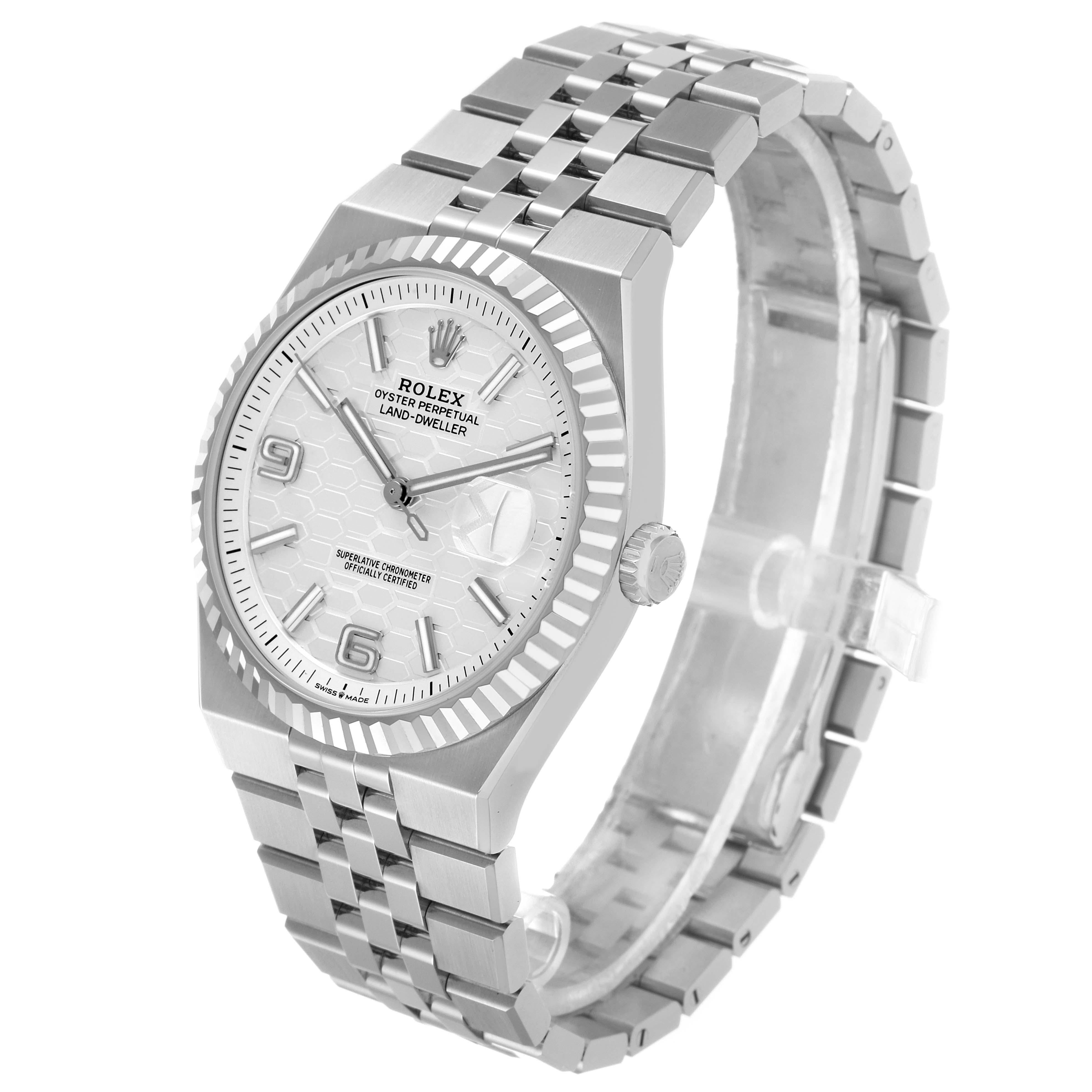 The Rolex Land-Dweller watch is shown at a three-quarter angle, displaying the face, bezel, crown, and bracelet.