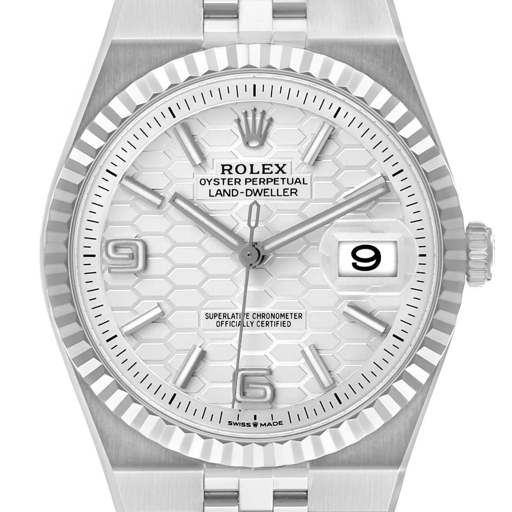 The Rolex Land-Dweller watch is shown from a front angle, displaying the textured dial, hour markers, and date window.