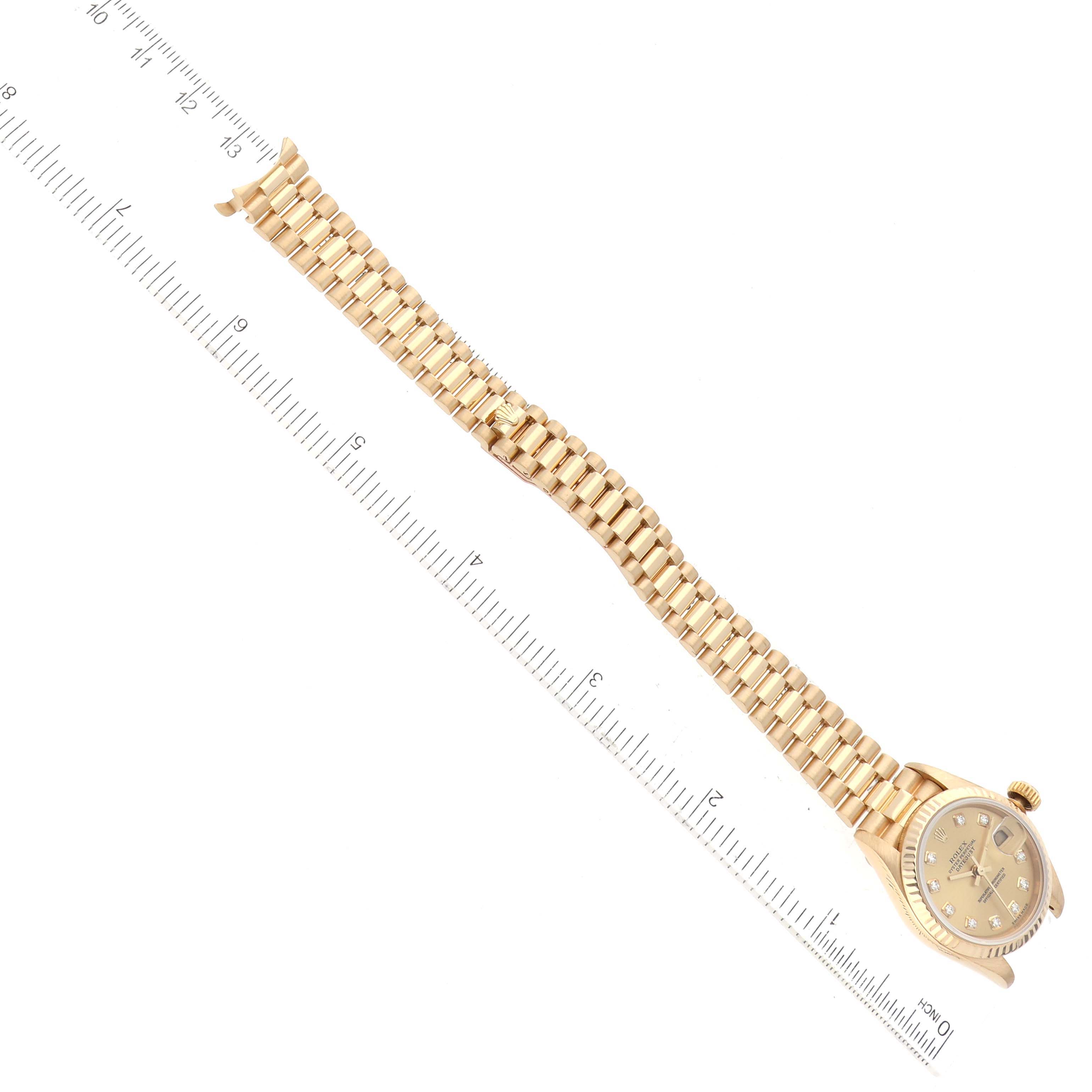 The image shows a Rolex President 79178 Women
s Yellow Gold Champagne Dial 79178 Women
s Yellow Gold Champagne Dial model watch placed diagonally with the full bracelet and face visible, alongside a ruler for scale.