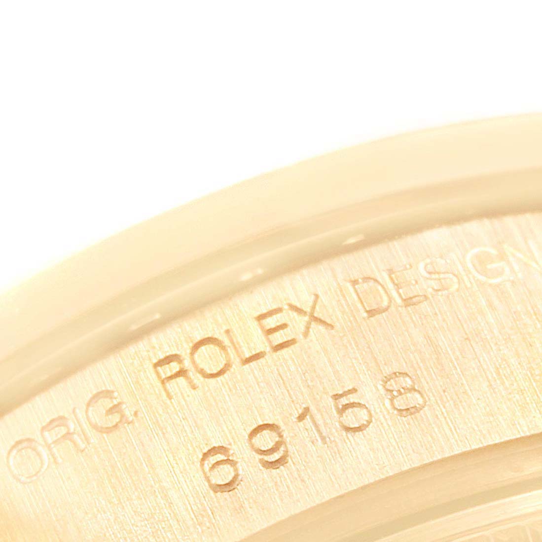 This image shows a close-up of the serial number and "ROLEX DESIGN" inscription on the case of a Rolex President 69158 Women
s Yellow Gold Black Dial 69158 Women
s Yellow Gold Black Dial model.